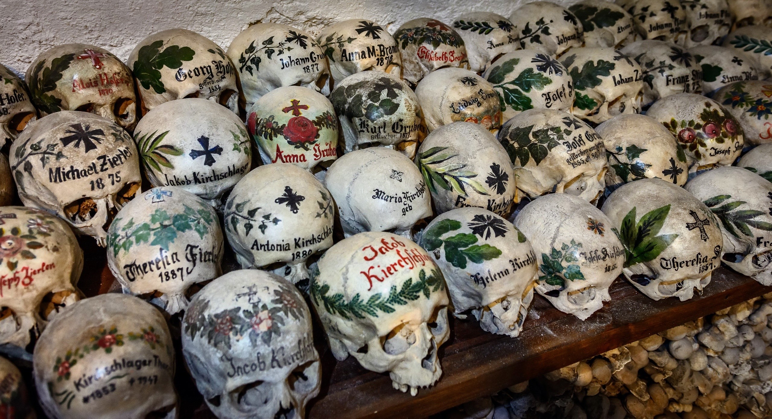Painted skulls with names and dates in a bone church HD Wallpaper