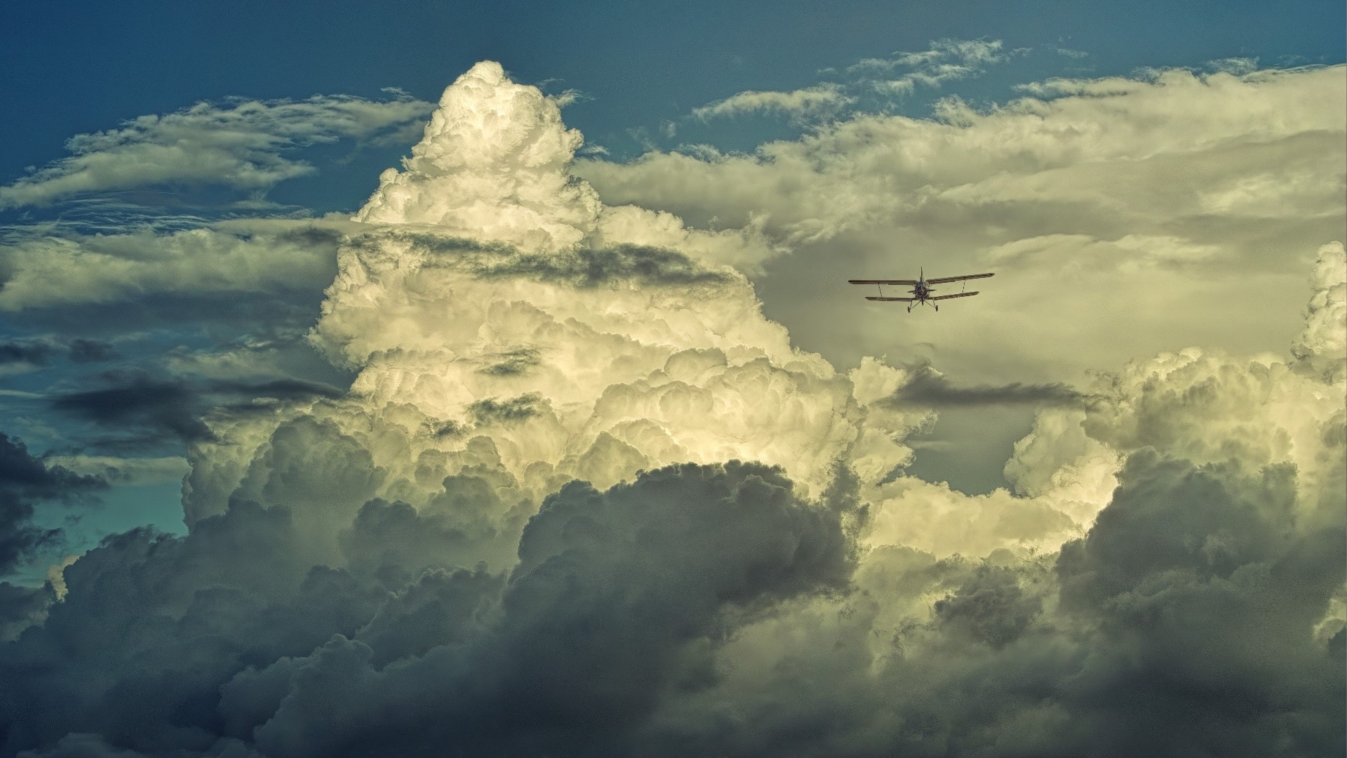 Biplane flying through dramatic clouds HD Wallpaper