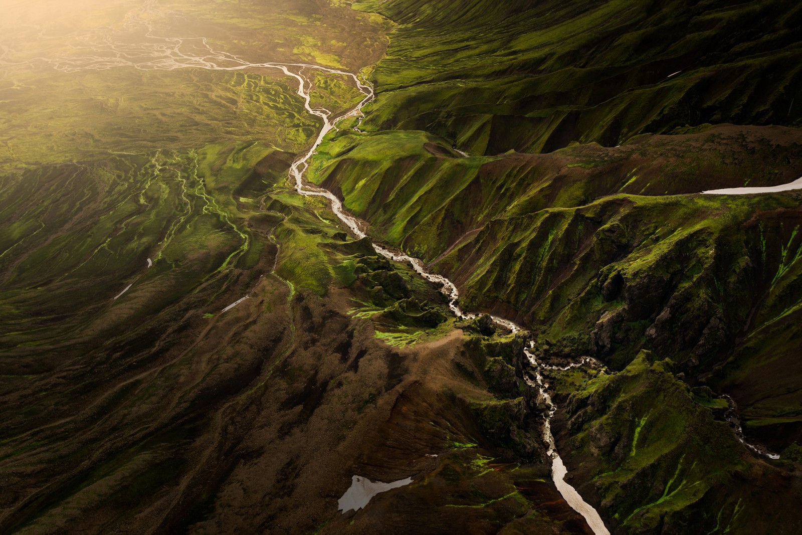 Aerial view of a river flowing through green mountains in Iceland HD Wallpaper