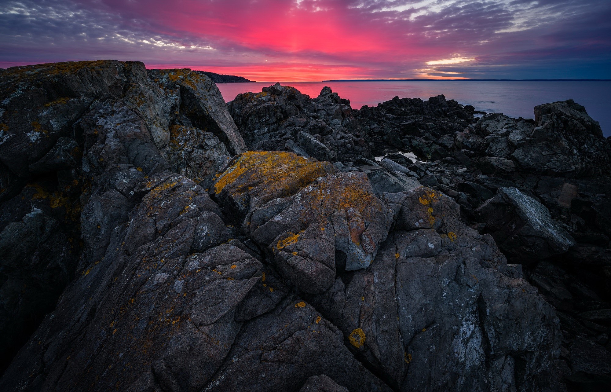 Rocky coast at sunset with vibrant pink sky HD Wallpaper