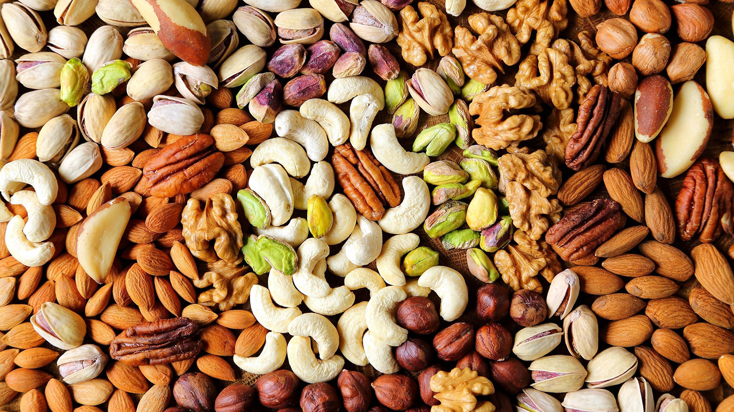 Assortment of nuts including walnuts, pistachios, almonds, and pecans HD Wallpaper
