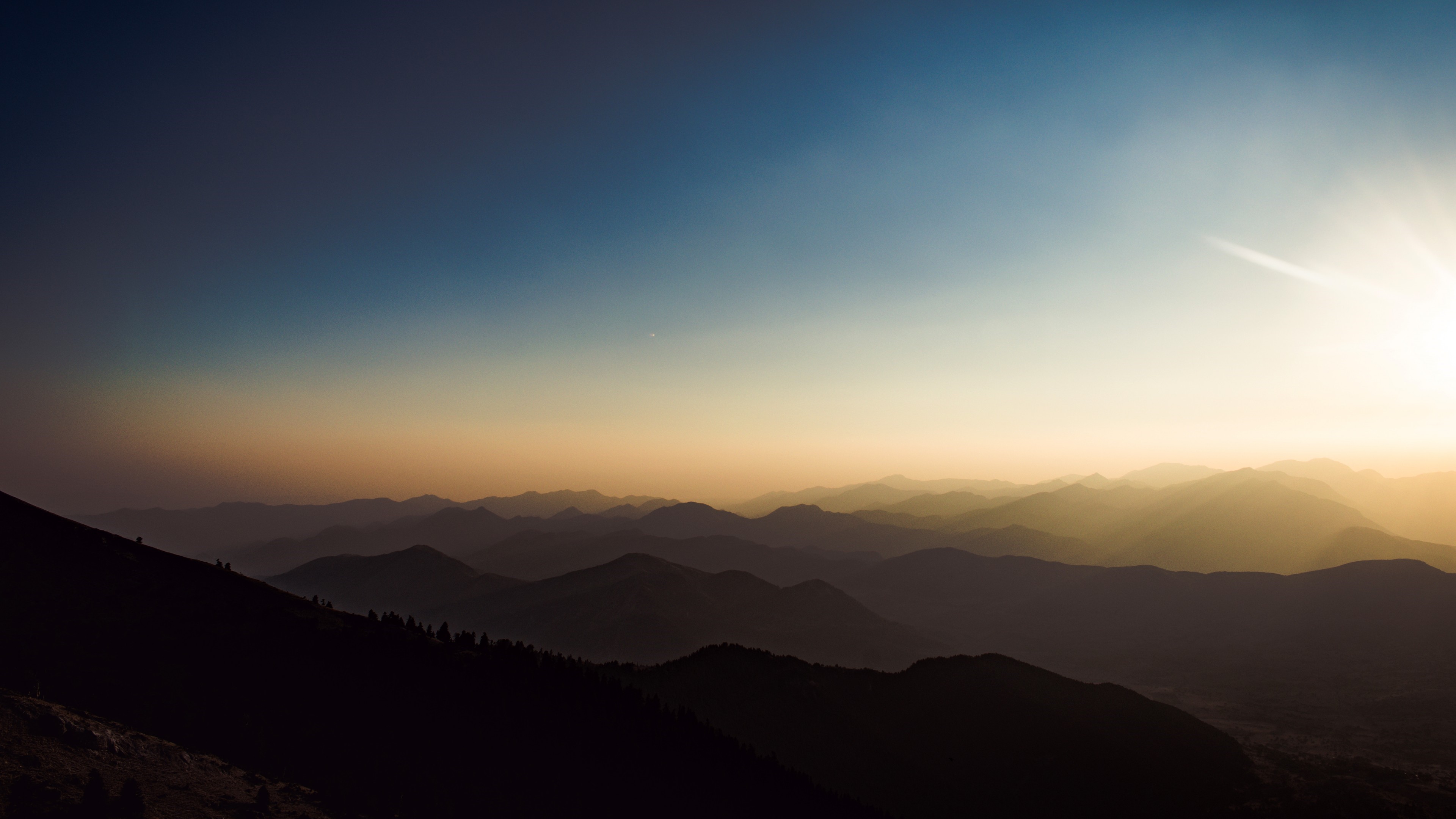 Sunset over layered mountains with blue and yellow sky HD Wallpaper