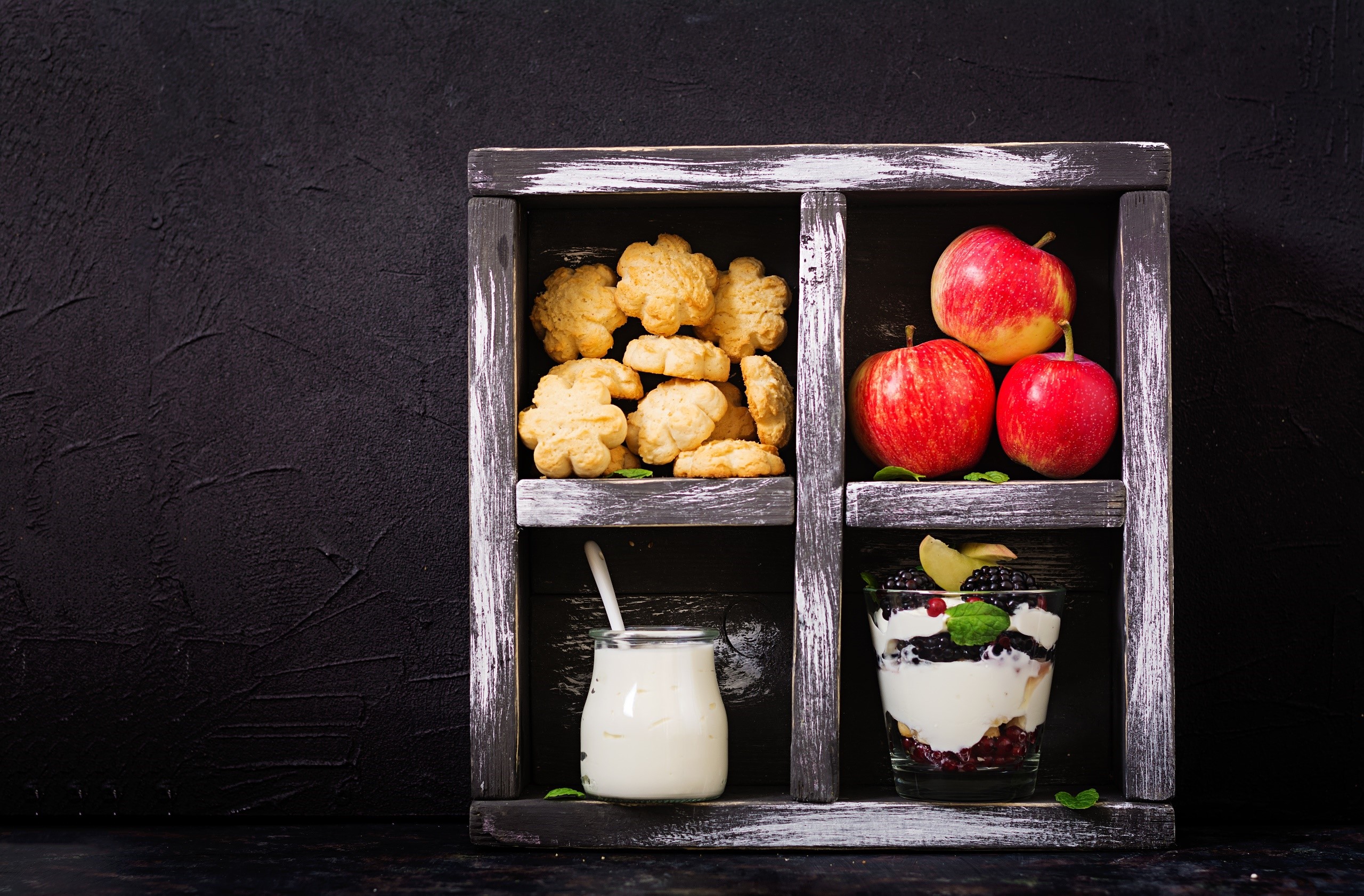 Cookies, apples, yogurt, and berry parfait in a wooden box HD Wallpaper