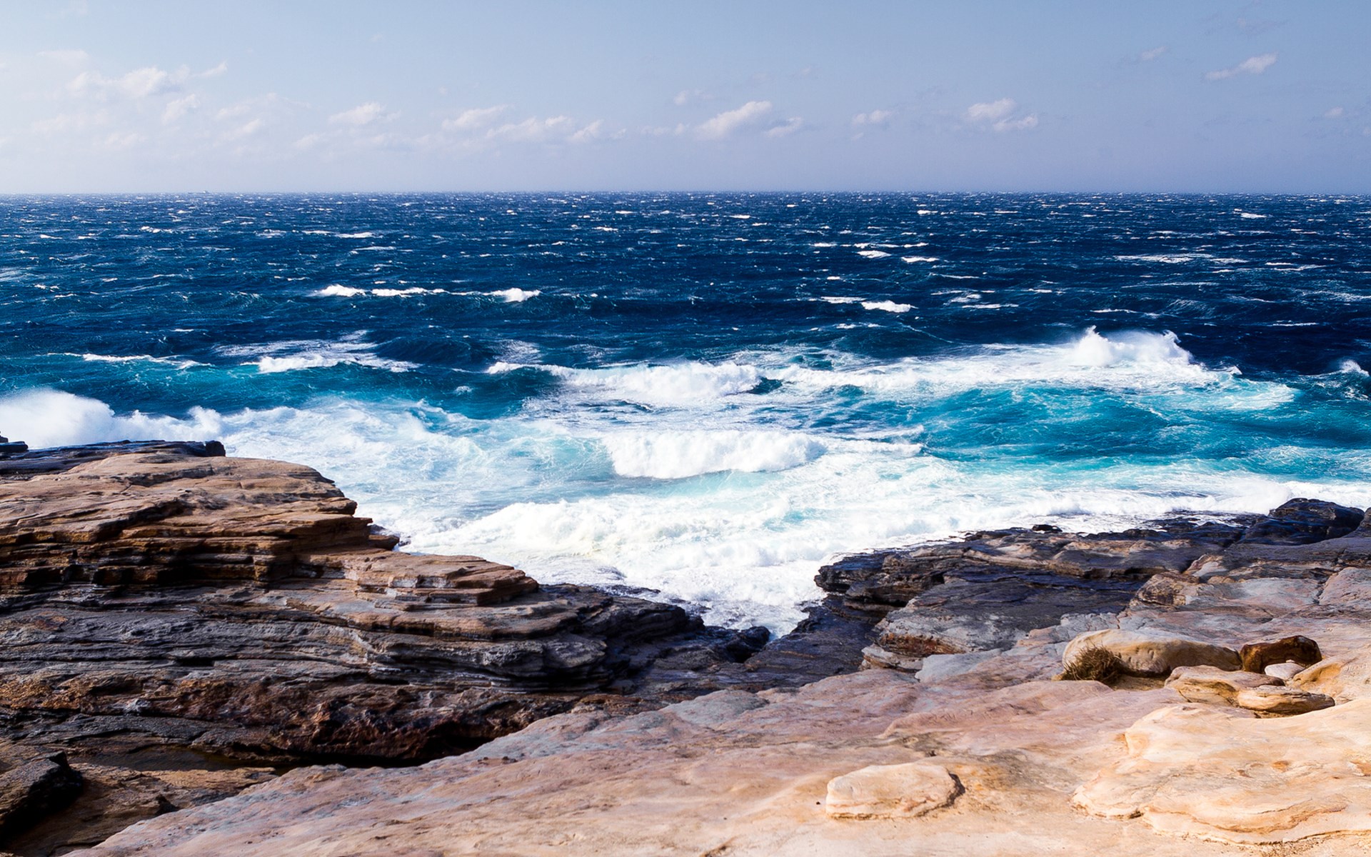 Waves crashing on rocky shore under a cloudy sky HD Wallpaper