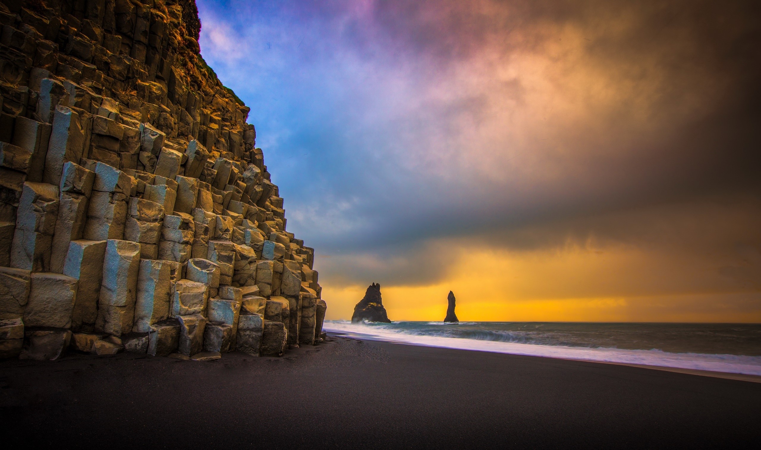 Basalt columns on a black sand beach with sea stacks HD Wallpaper