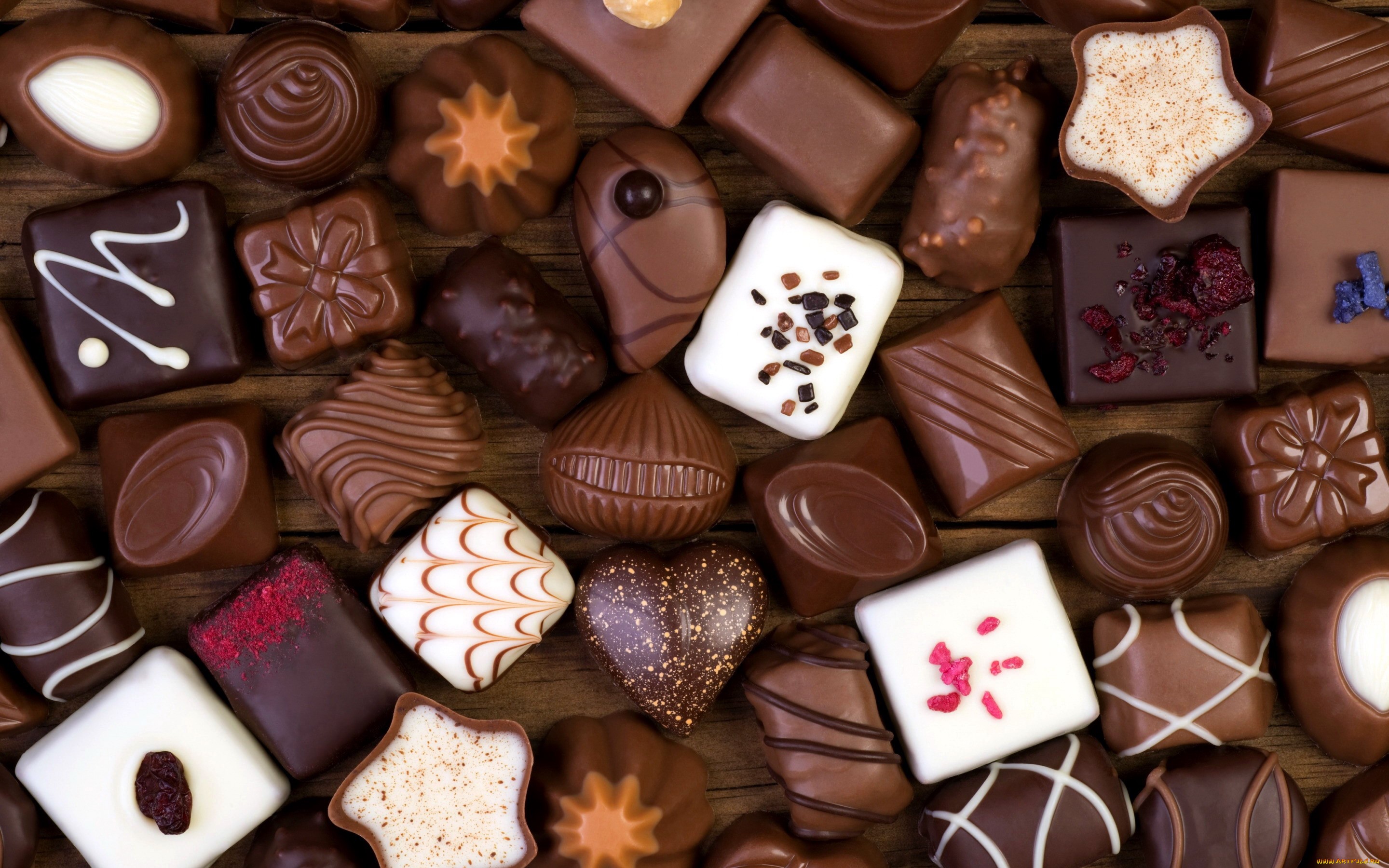 Assortment of chocolates on a wooden surface HD Wallpaper
