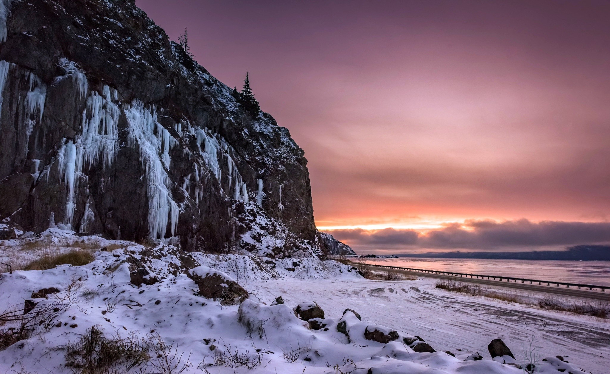 Winter scene with icy cliff and sunset over water HD Wallpaper