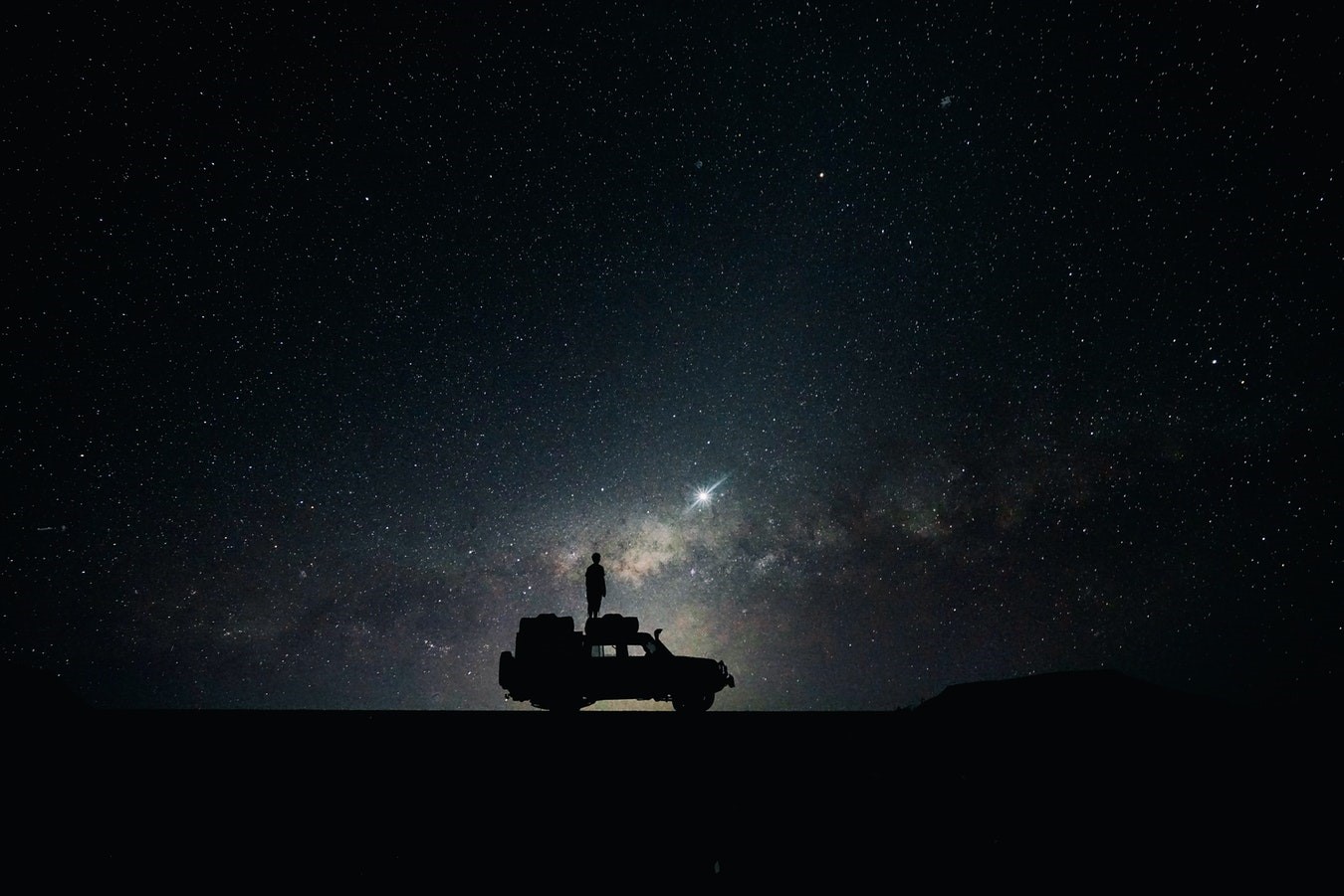 Silhouette of a person on a car under the stars HD Wallpaper