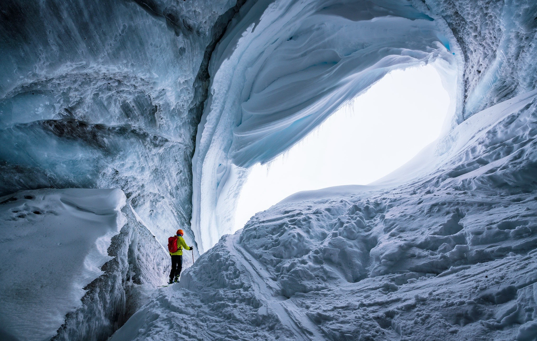 Person in ice cave with backpack and ski poles HD Wallpaper