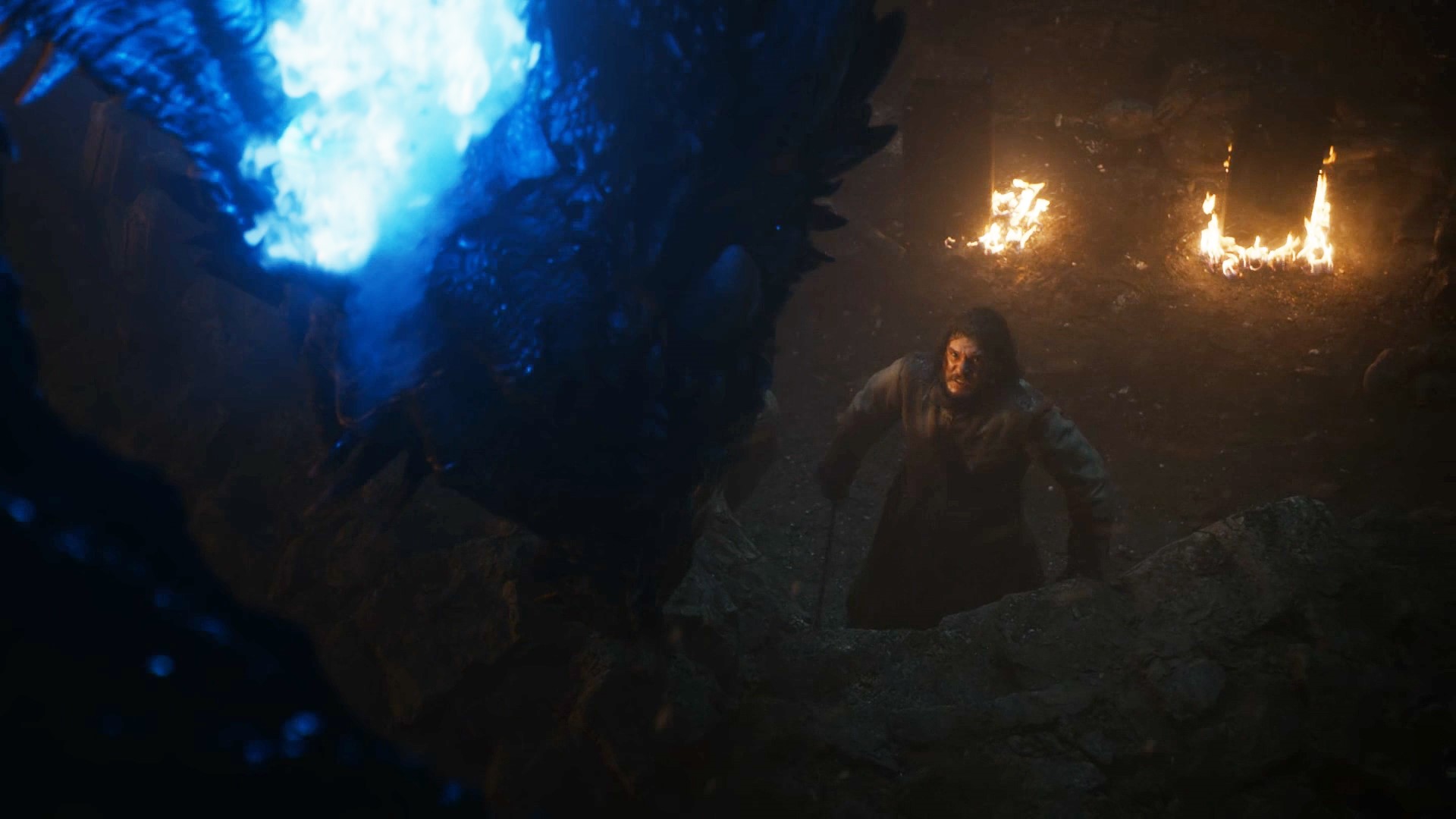 Jon Snow facing a dragon breathing blue fire in a cave HD Wallpaper