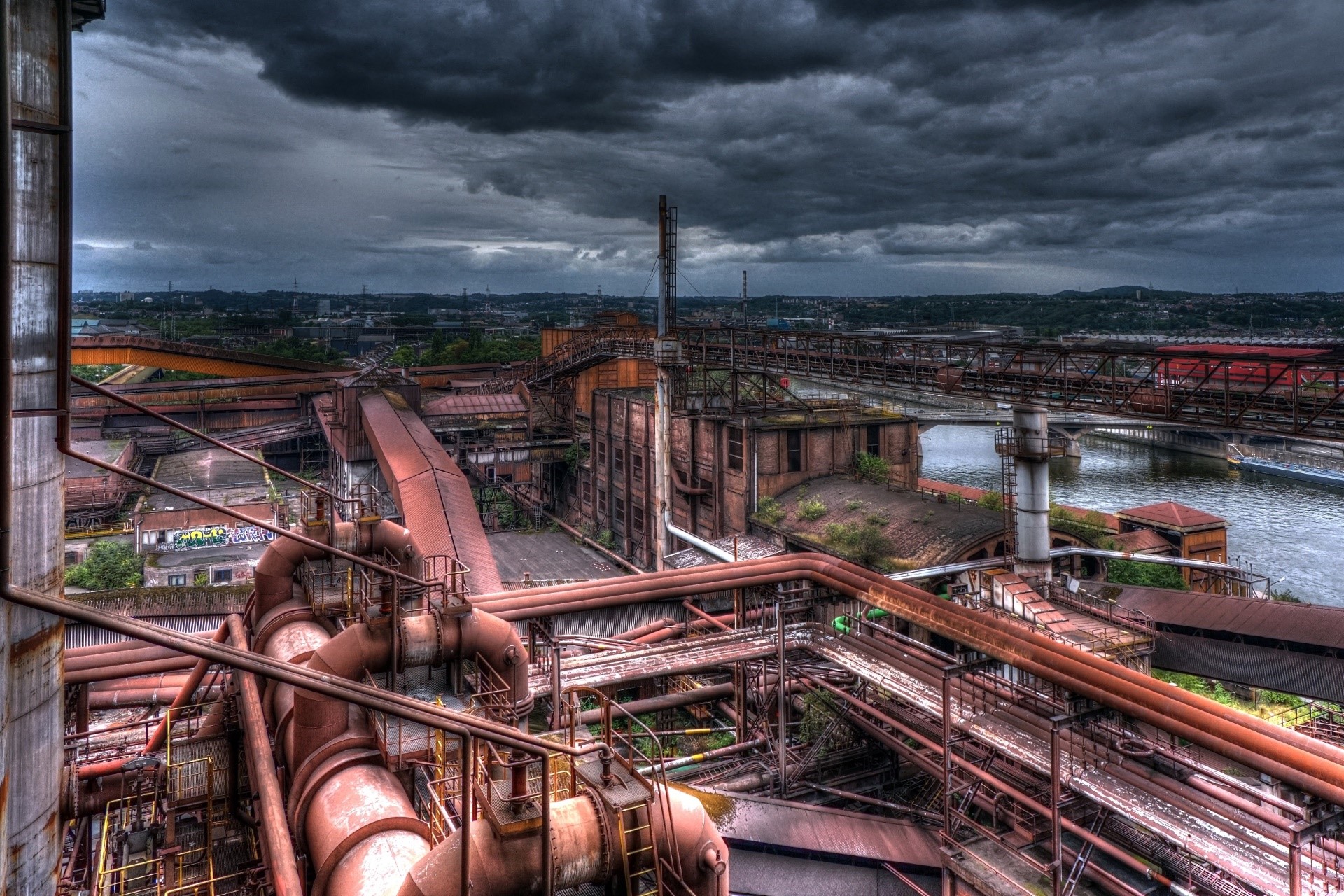 Abandoned industrial complex with a river and cityscape HD Wallpaper
