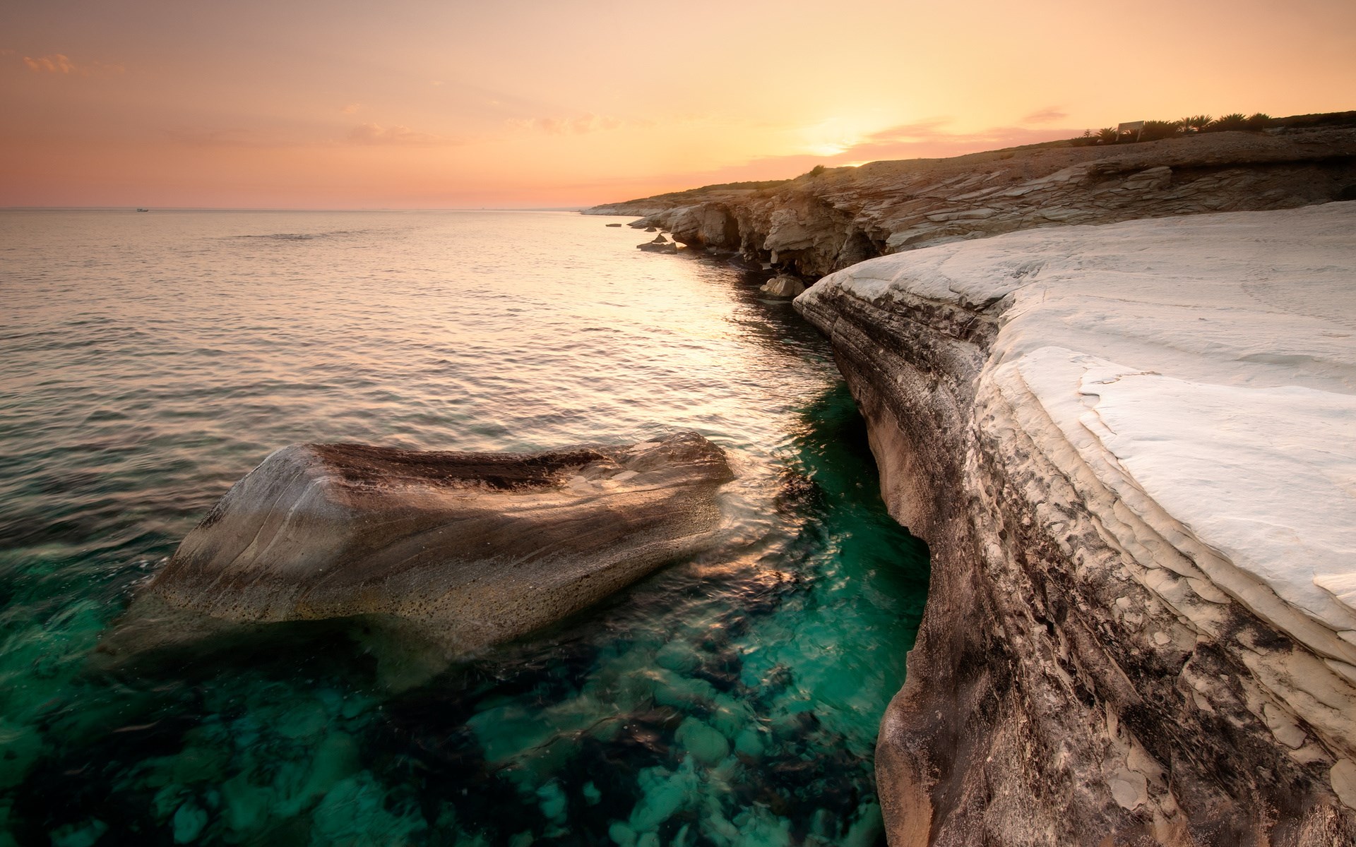 Rocky coastline at sunset with clear turquoise water HD Wallpaper