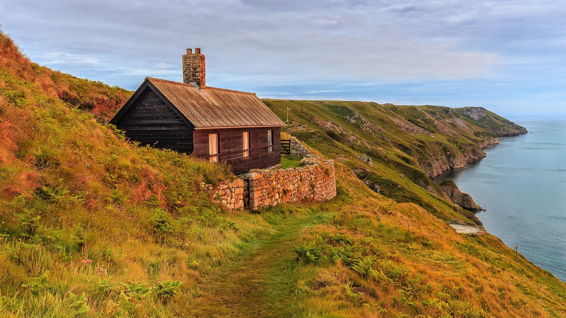 Wooden cabin on a grassy cliff overlooking the sea HD Wallpaper