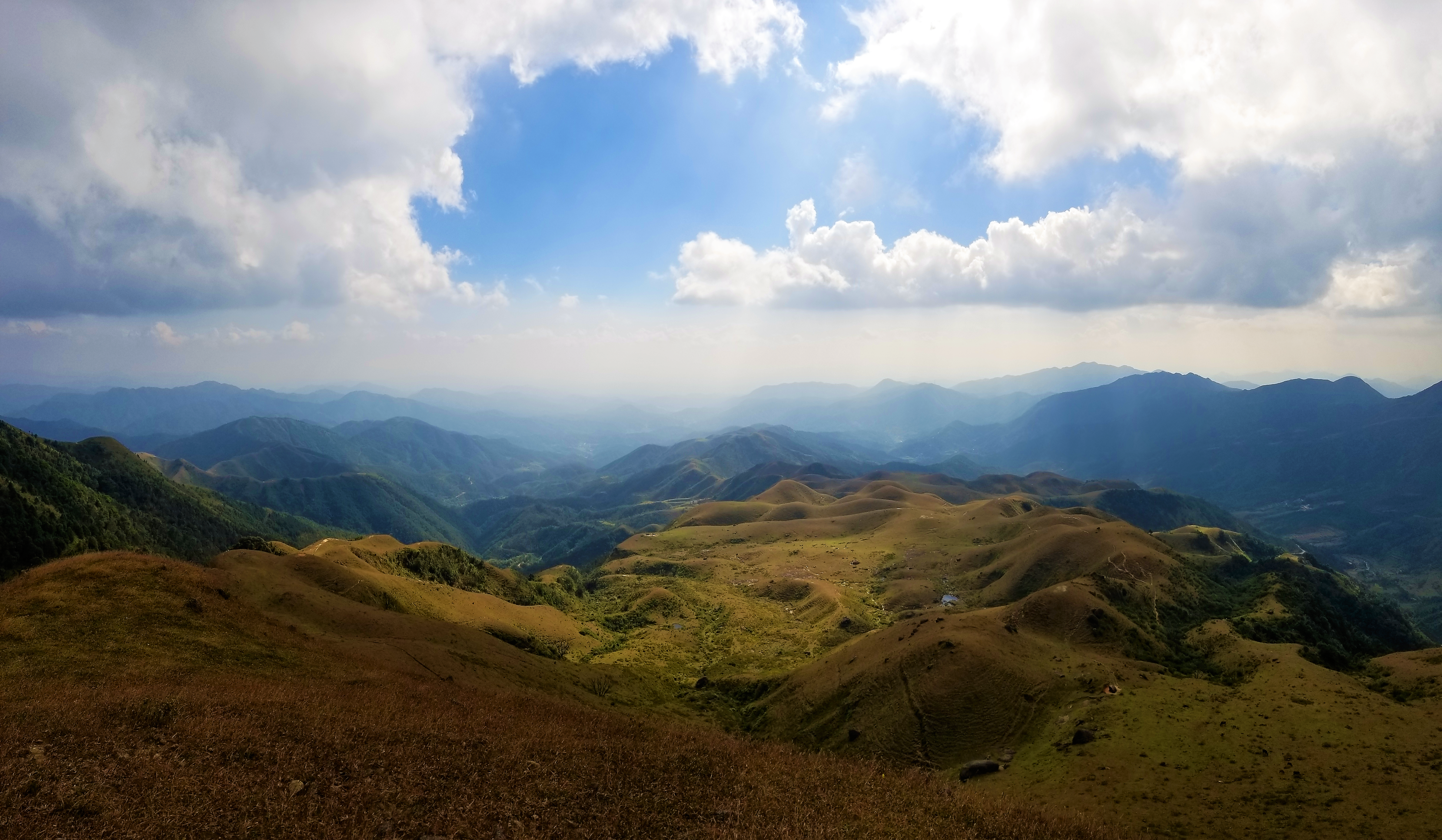 Panoramic view of rolling mountains under a cloudy sky HD Wallpaper