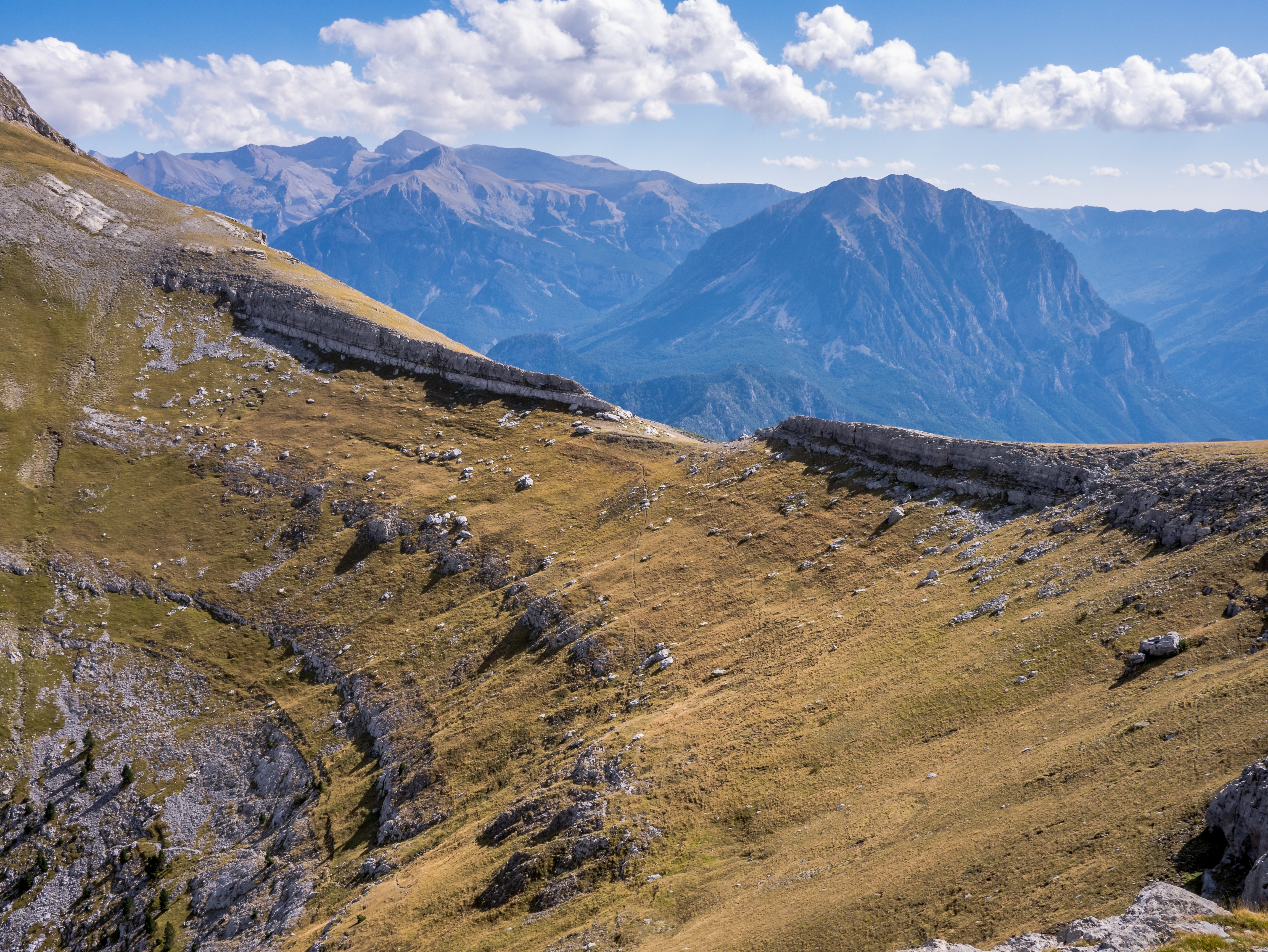 Mountain landscape with layered rock formations and distant peaks HD Wallpaper