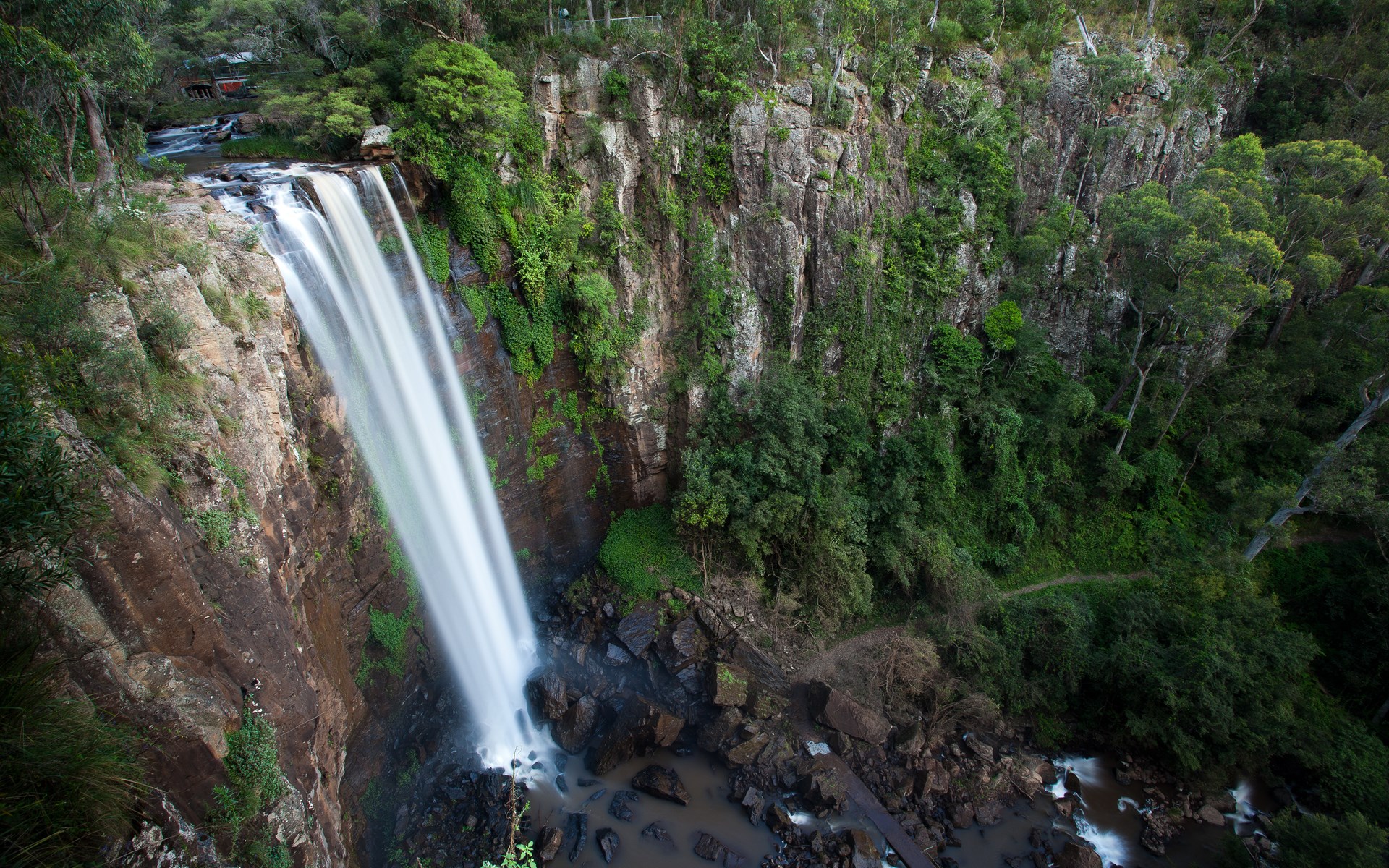 Waterfall cascading down a rocky cliff face HD Wallpaper