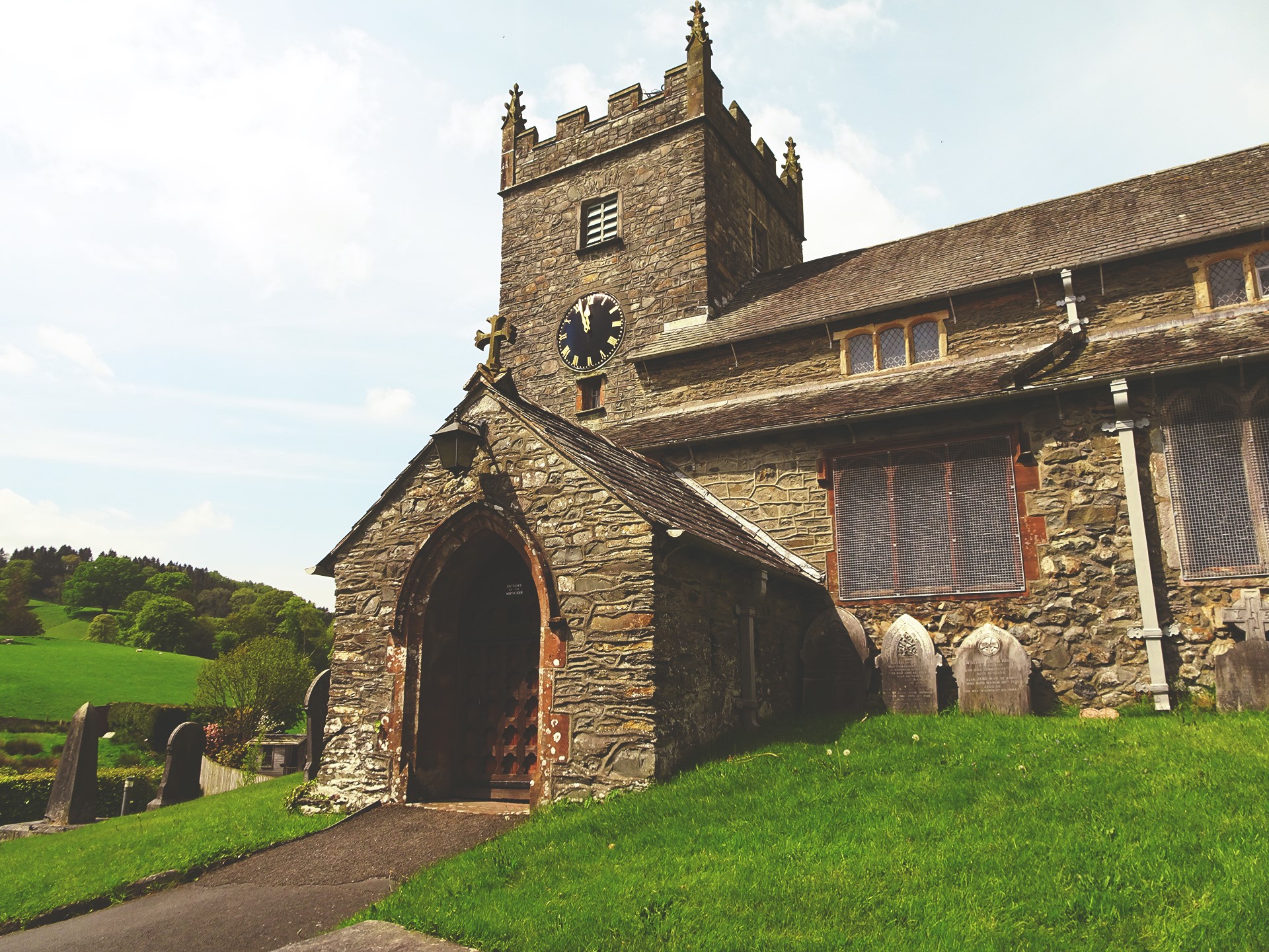Stone church with clock tower and gravestones HD Wallpaper