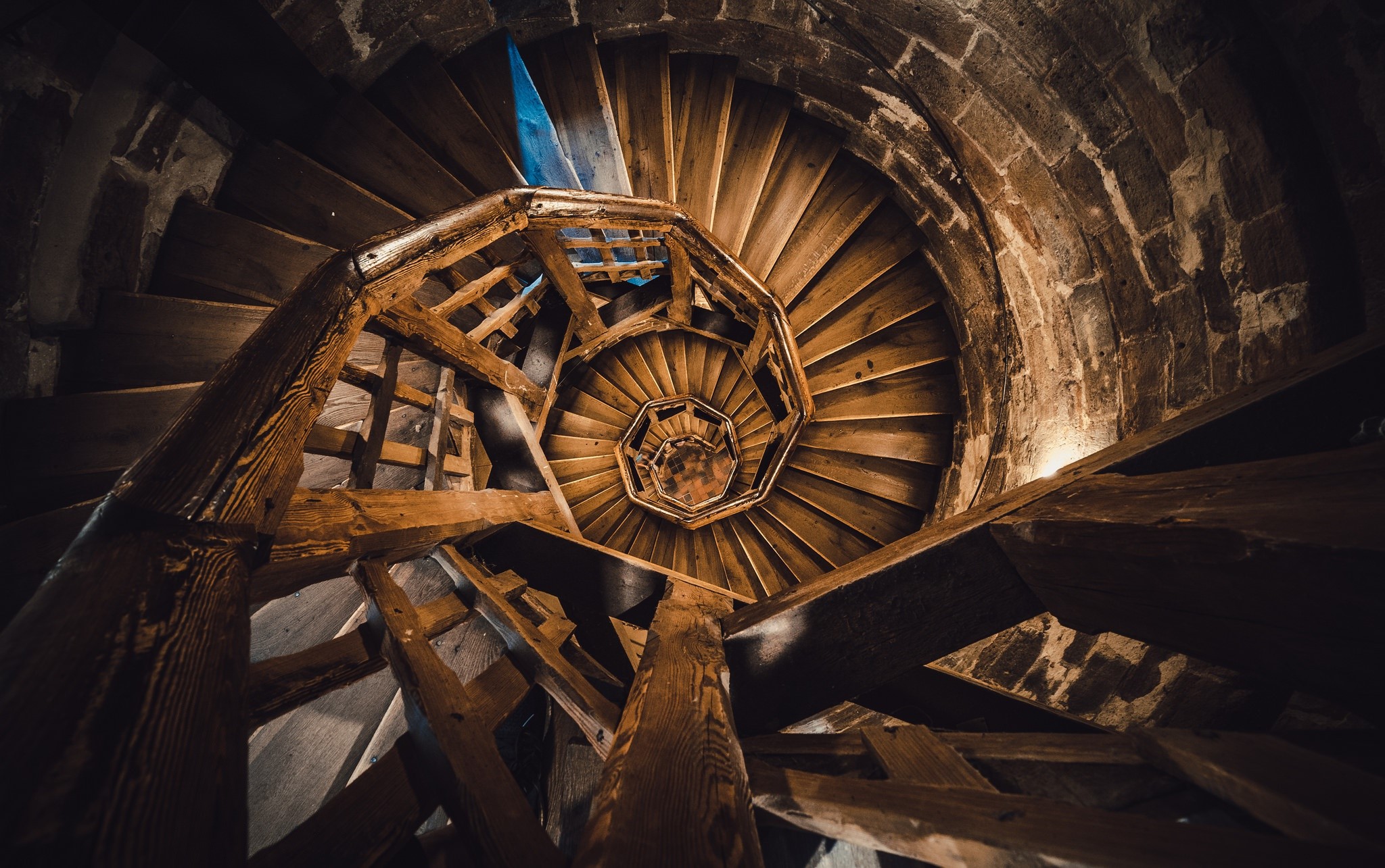 Spiral wooden staircase inside a stone building HD Wallpaper