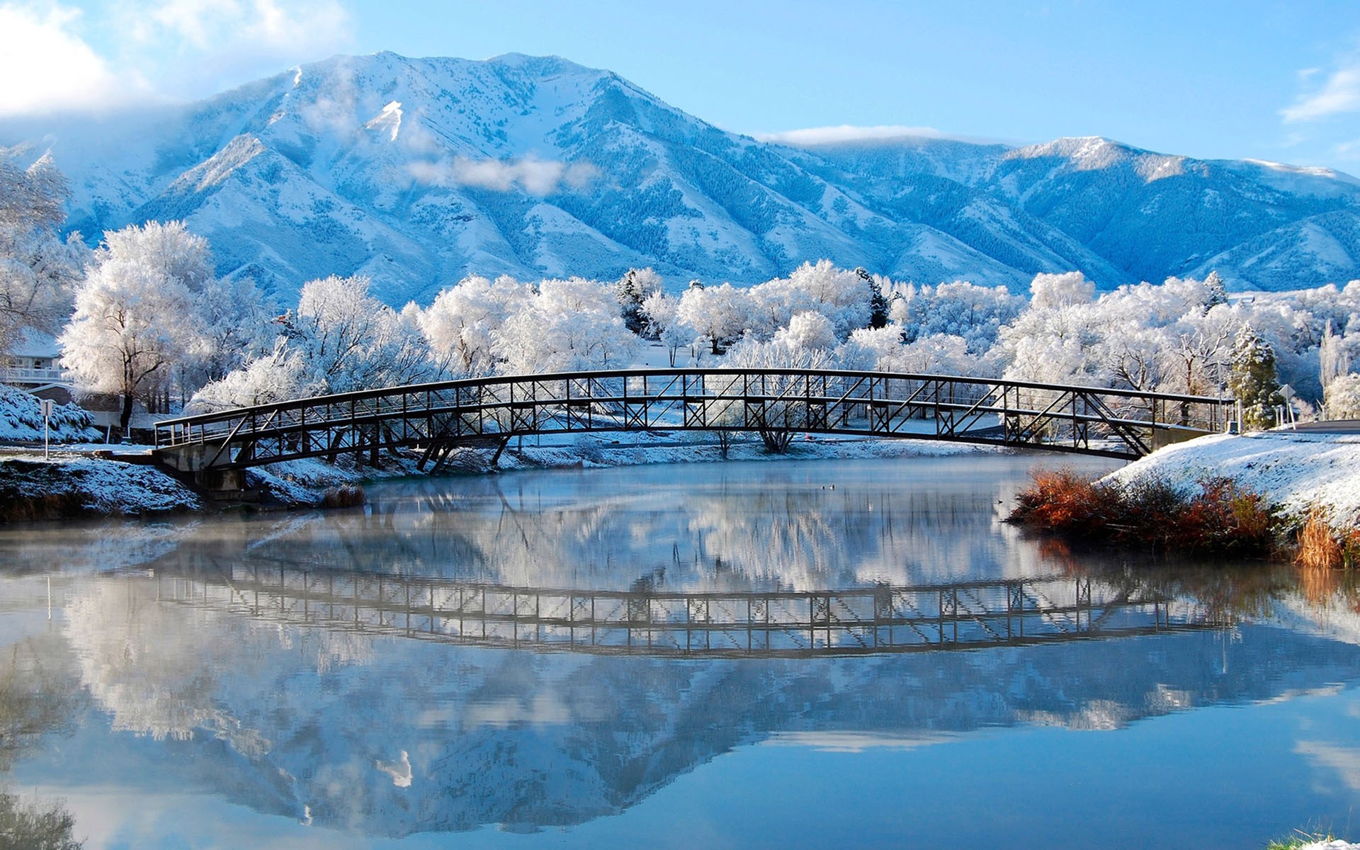 Snowy bridge over water with mountains and reflection HD Wallpaper