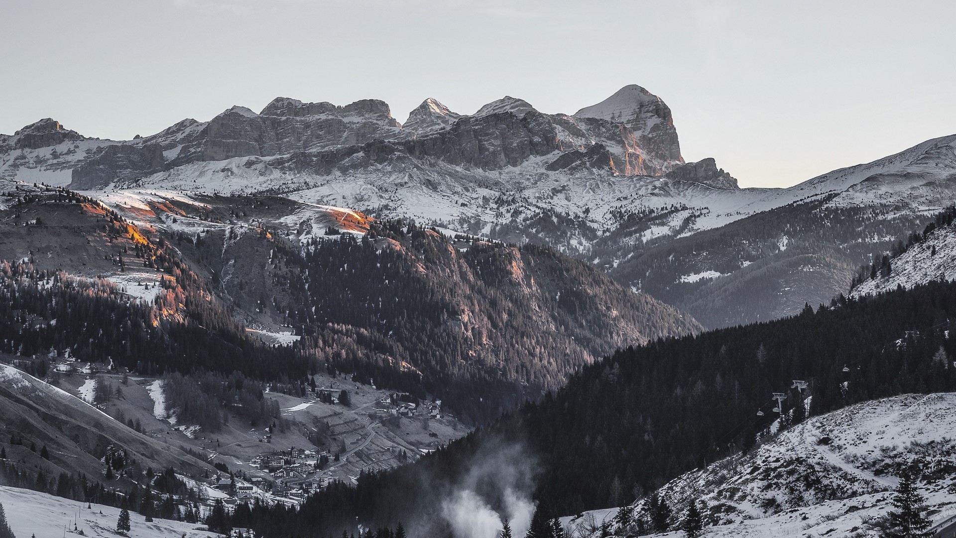 Snow-covered mountains with pine trees and a village HD Wallpaper