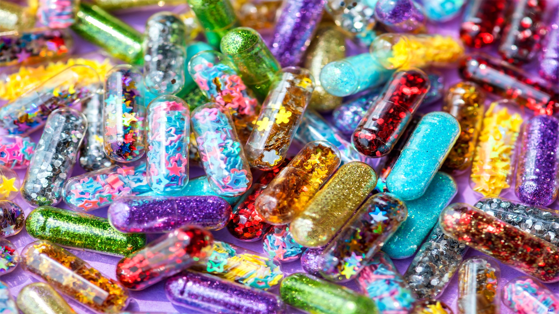 Colorful glitter-filled capsules on a purple background HD Wallpaper