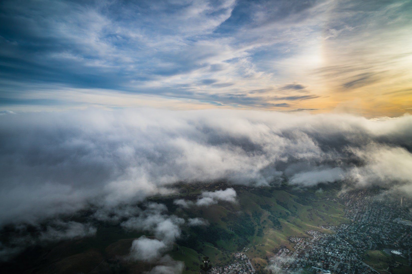 Aerial view of clouds over a city and hills HD Wallpaper