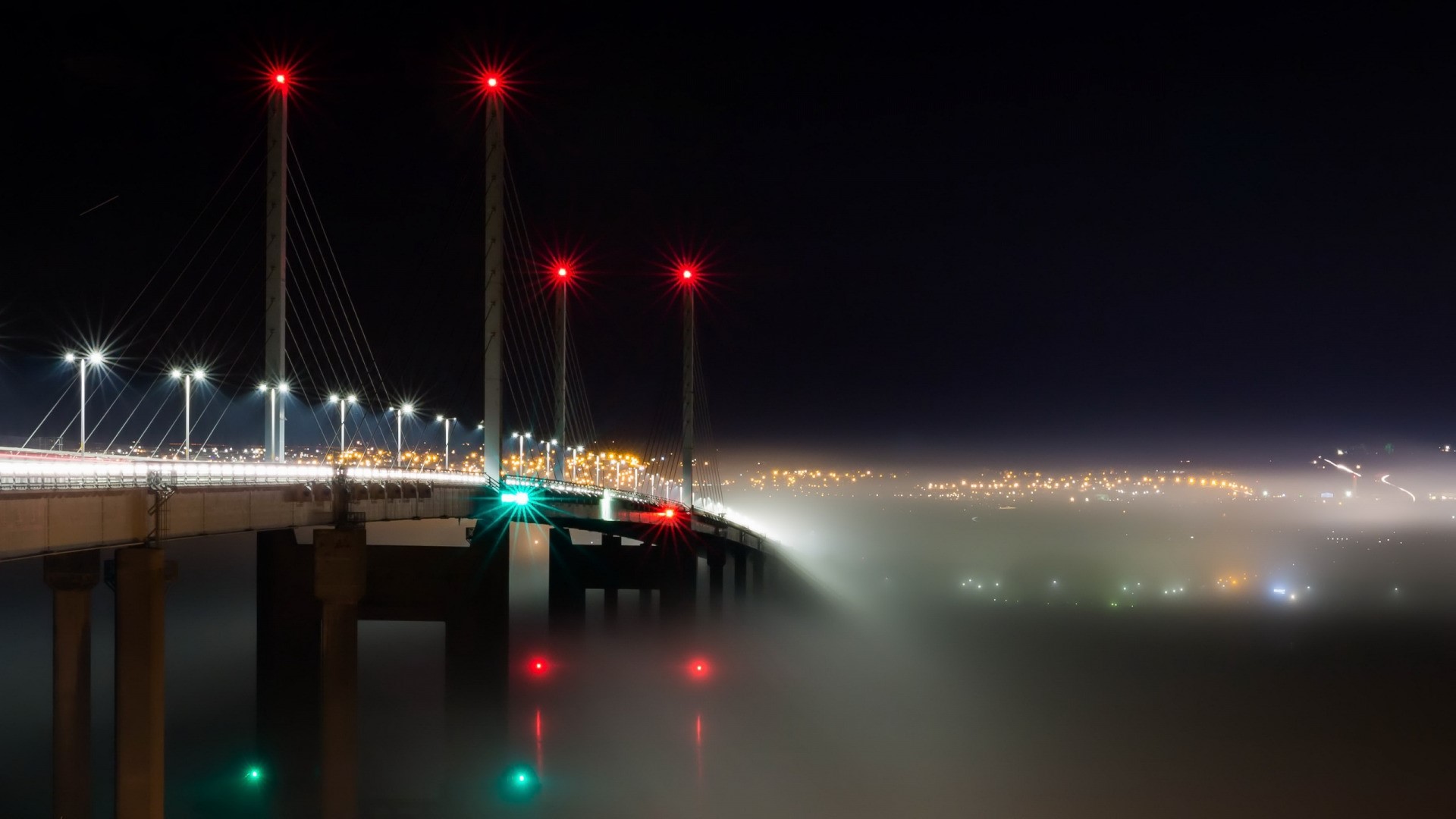 Bridge at night with fog and city lights HD Wallpaper
