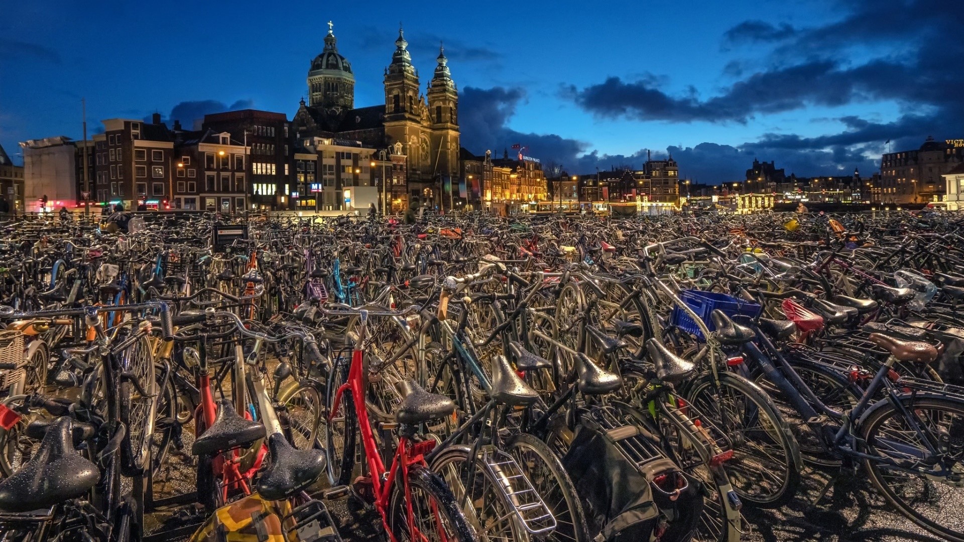Bicycles parked in front of buildings at dusk in Amsterdam HD Wallpaper