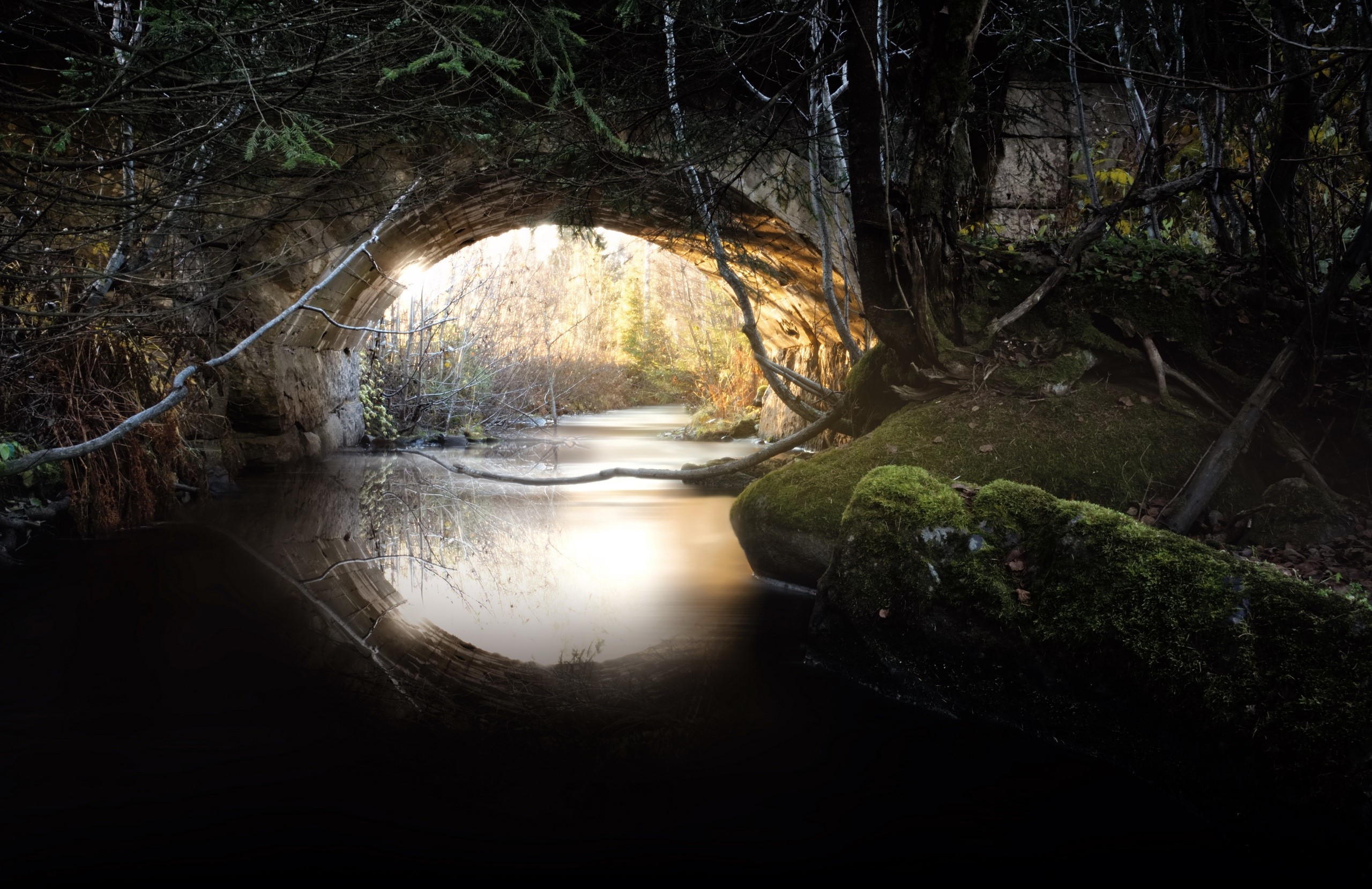 Stone bridge over a dark river with sunlight HD Wallpaper