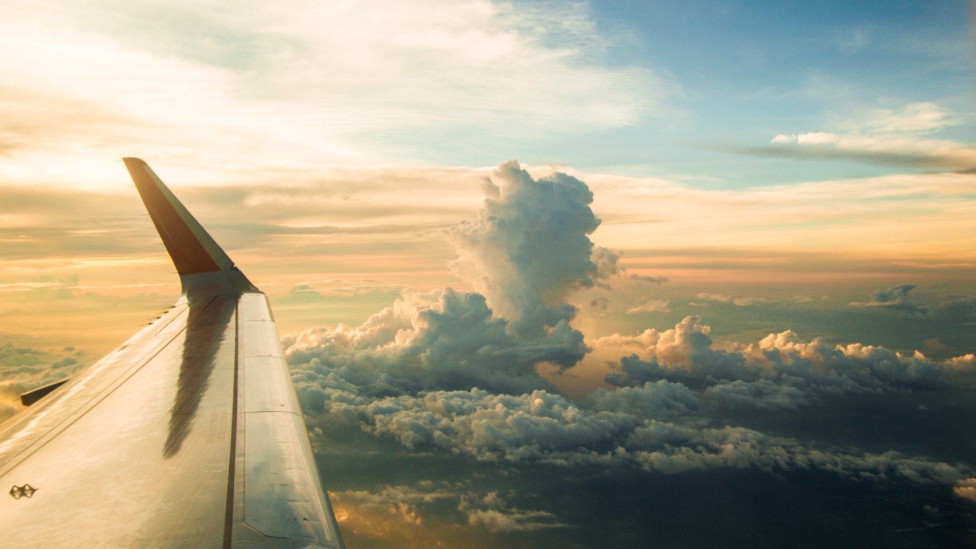 Airplane wing over clouds at sunset HD Wallpaper