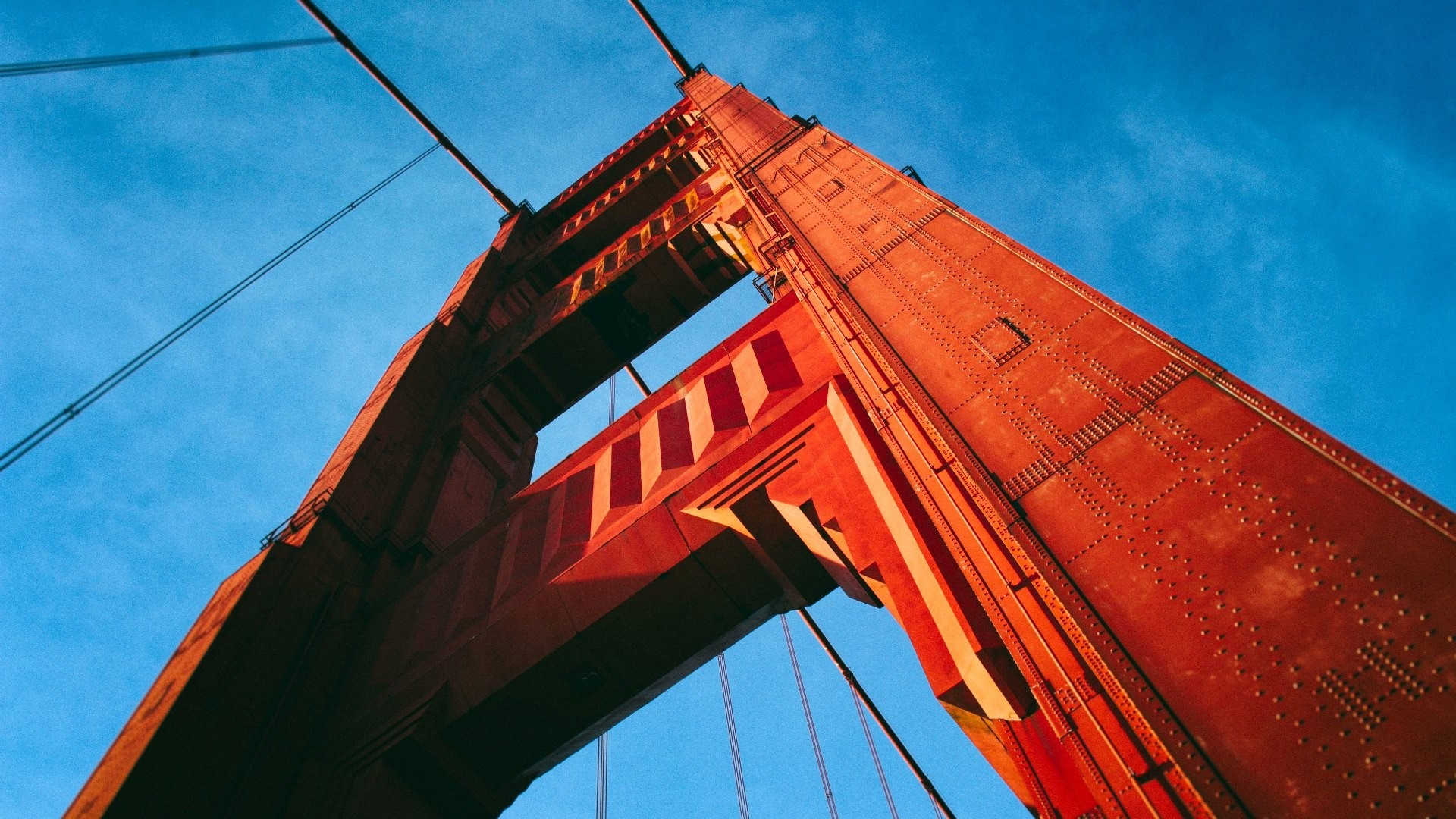 Golden Gate Bridge tower and cables against blue sky HD Wallpaper