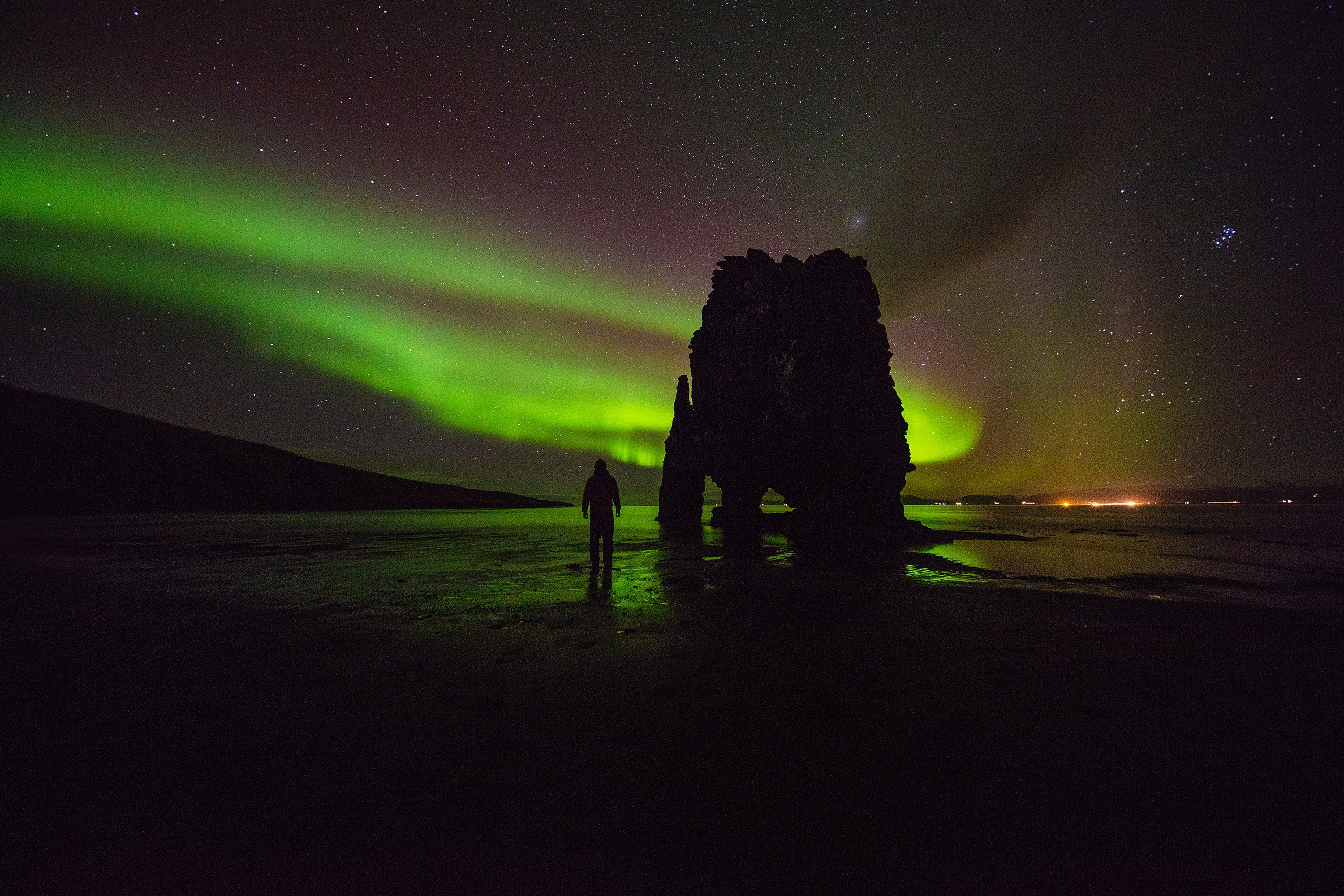 Person watching Aurora Borealis over rock formation HD Wallpaper