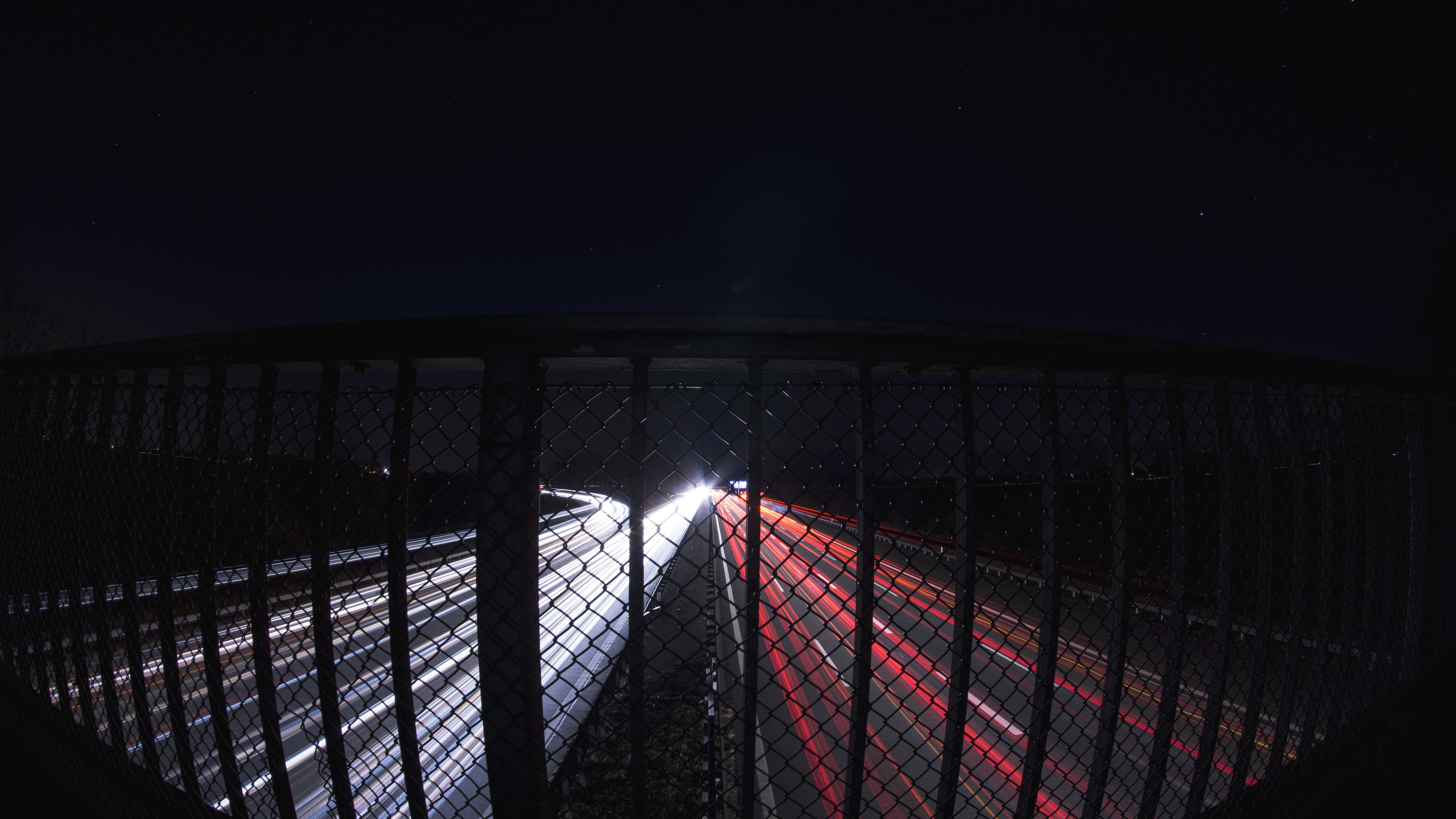 Long exposure of highway at night with fence HD Wallpaper