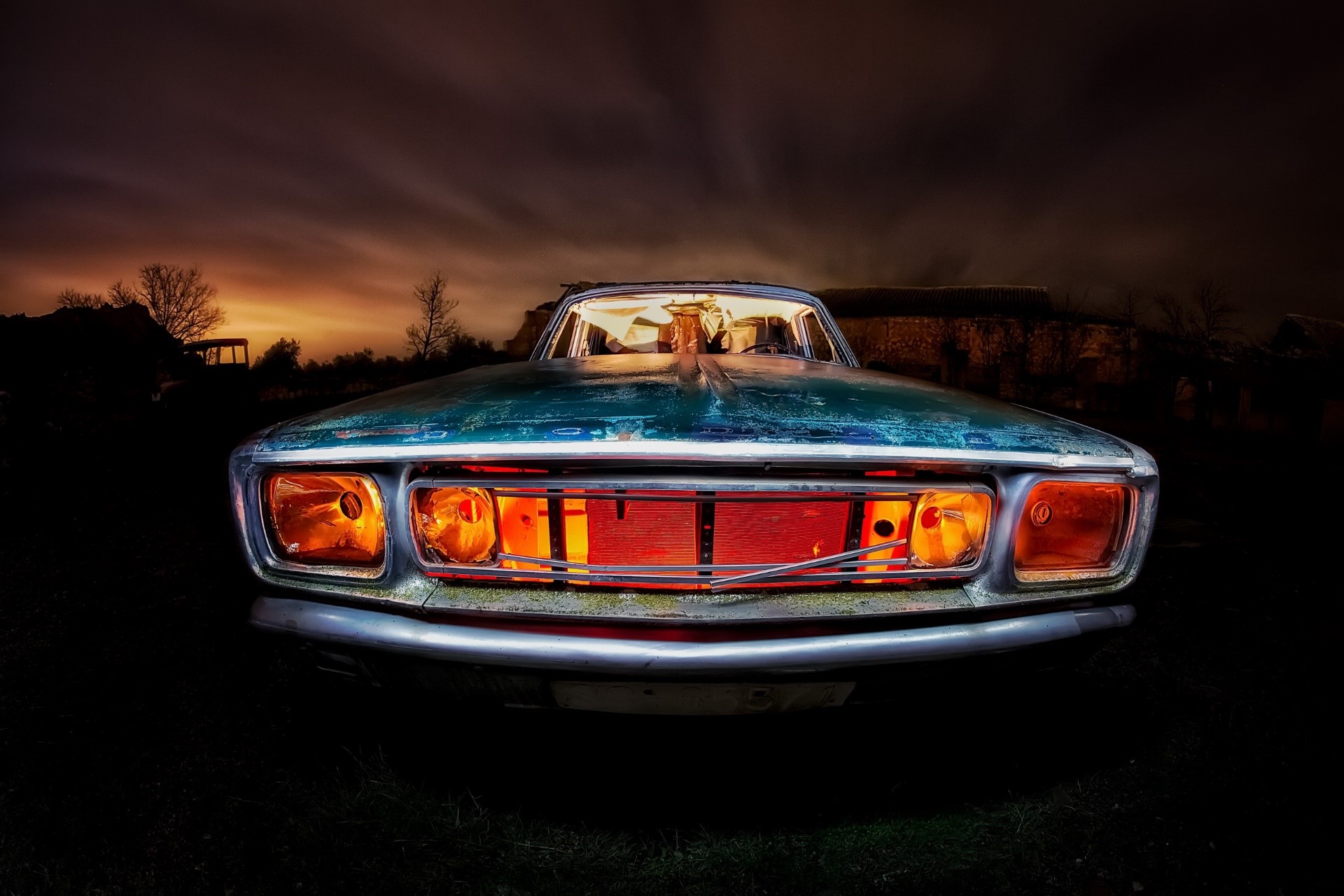 Old car with glowing orange headlights at night HD Wallpaper