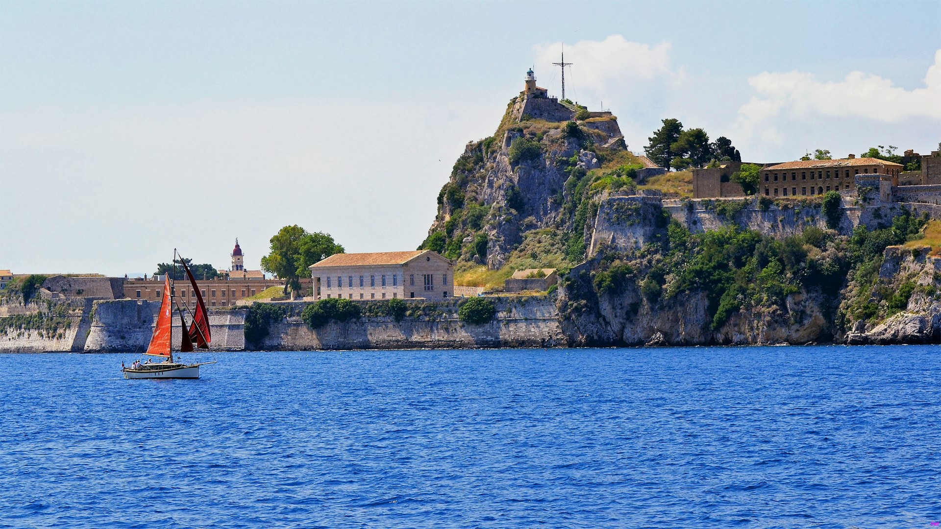 Sailboats near a fortified island with buildings and a lighthouse HD Wallpaper