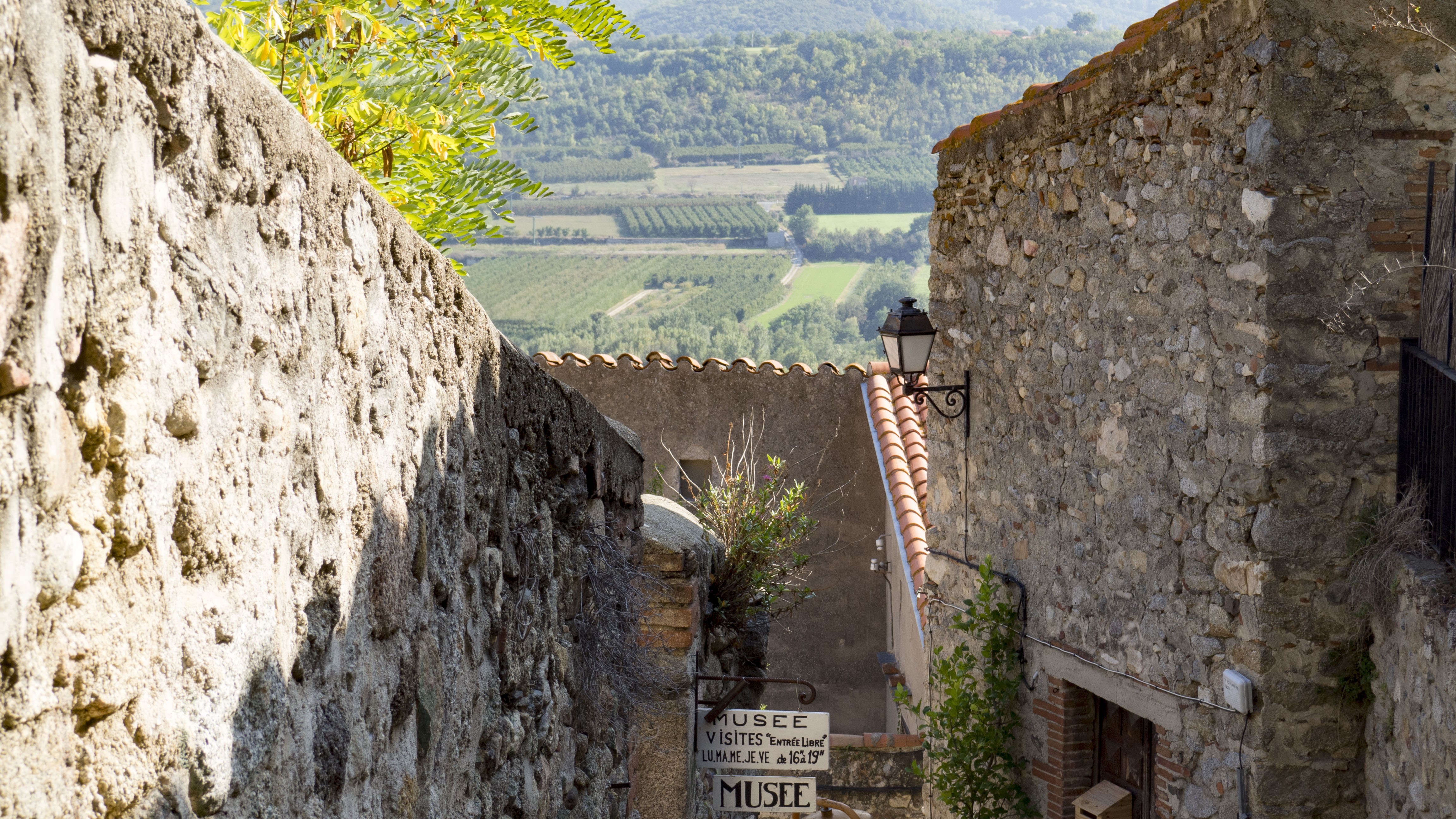 Village alley with stone walls and landscape view HD Wallpaper
