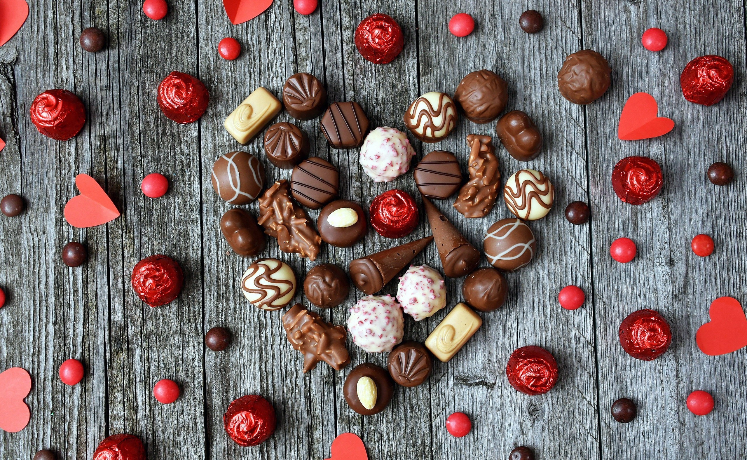 Heart shape of chocolates and candies on wooden surface HD Wallpaper