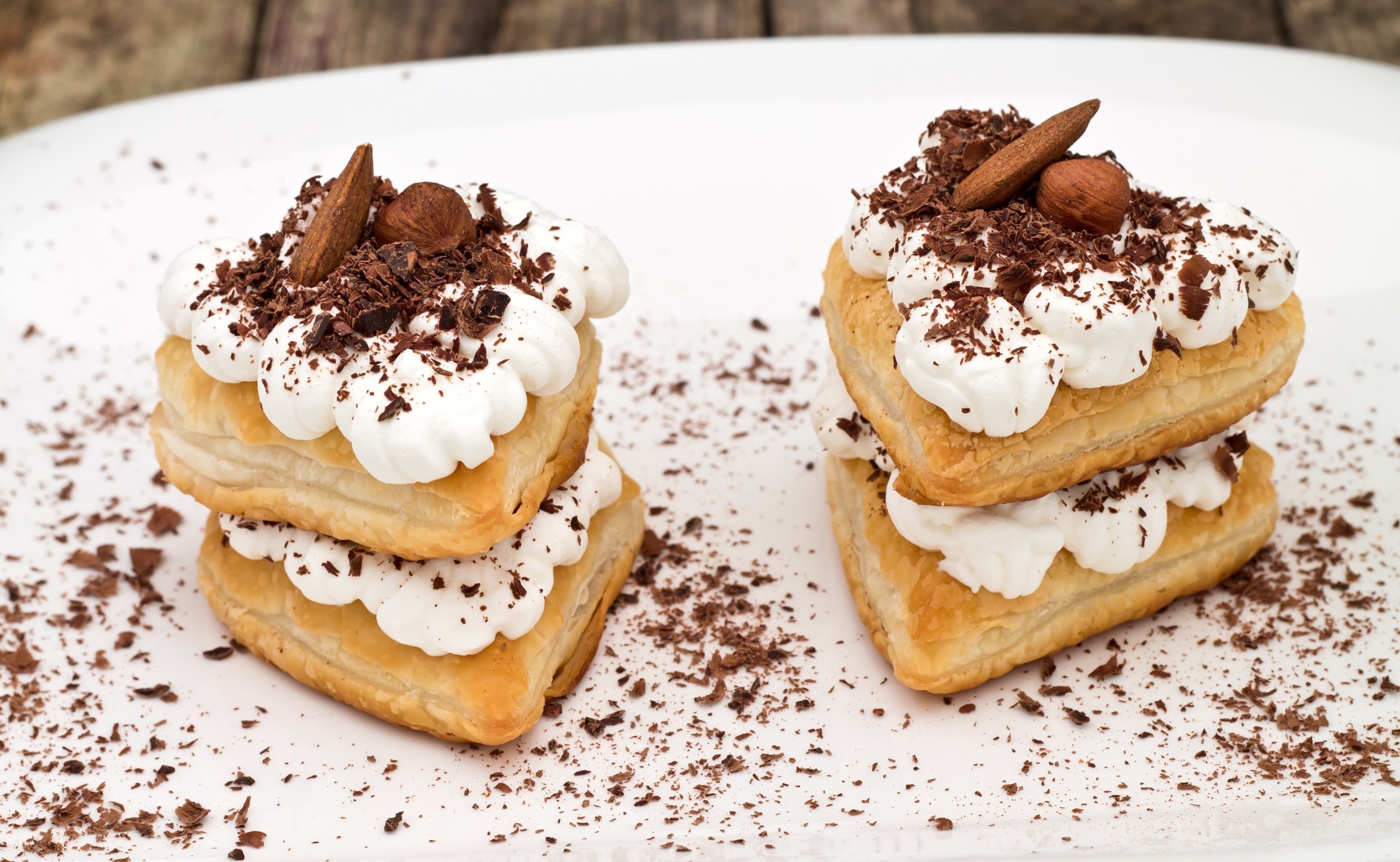 Two stacks of heart-shaped puff pastry desserts with whipped cream and chocolate shavings HD Wallpaper