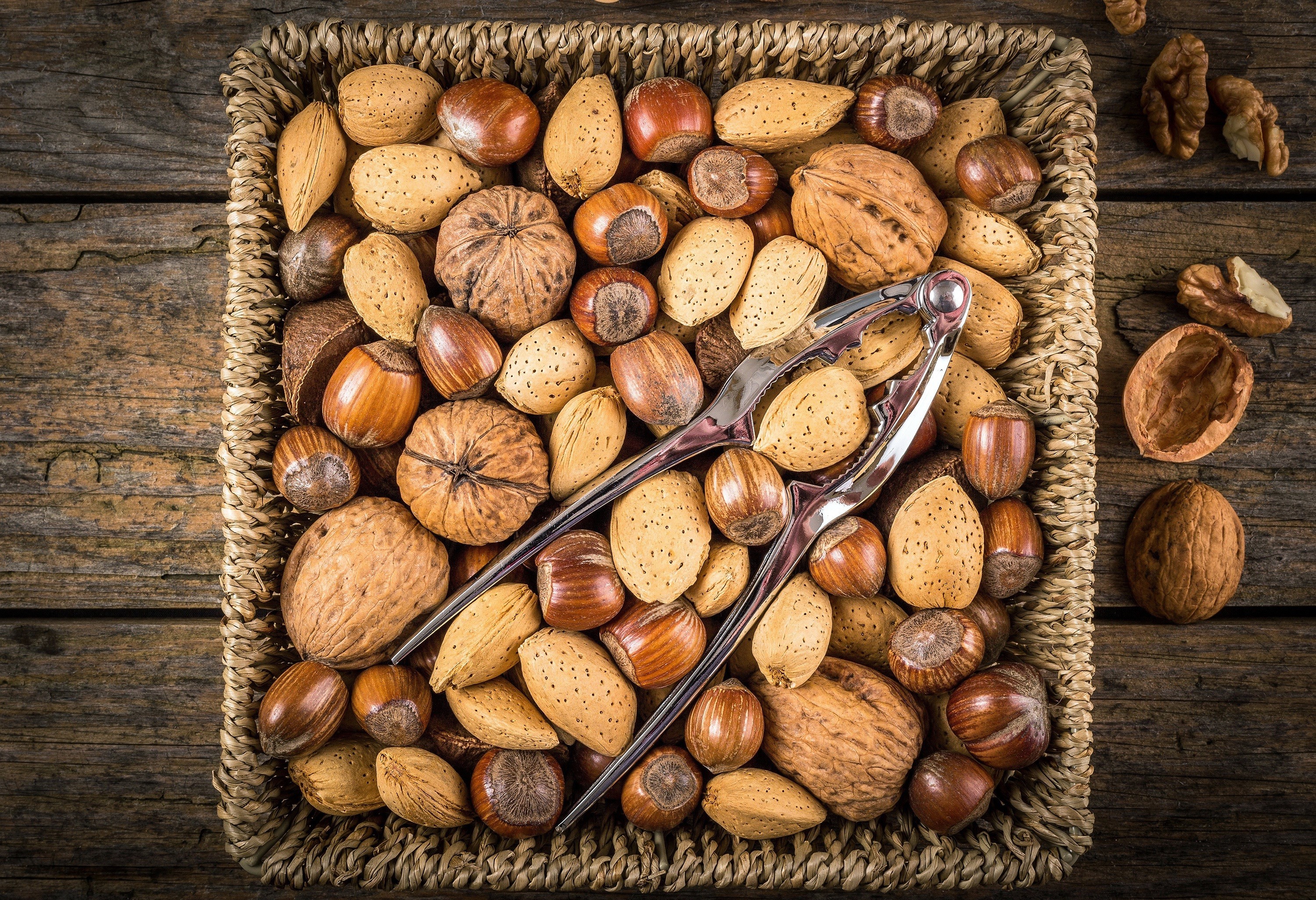 Basket of nuts with a nutcracker on a wooden surface HD Wallpaper