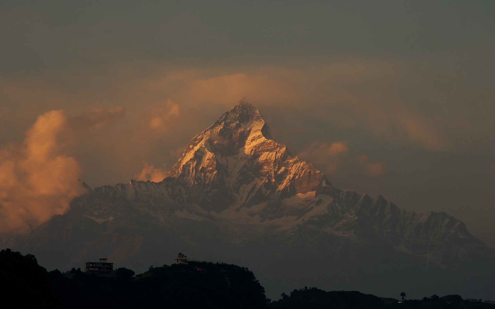 Snowy mountain peak illuminated by golden hour light HD Wallpaper