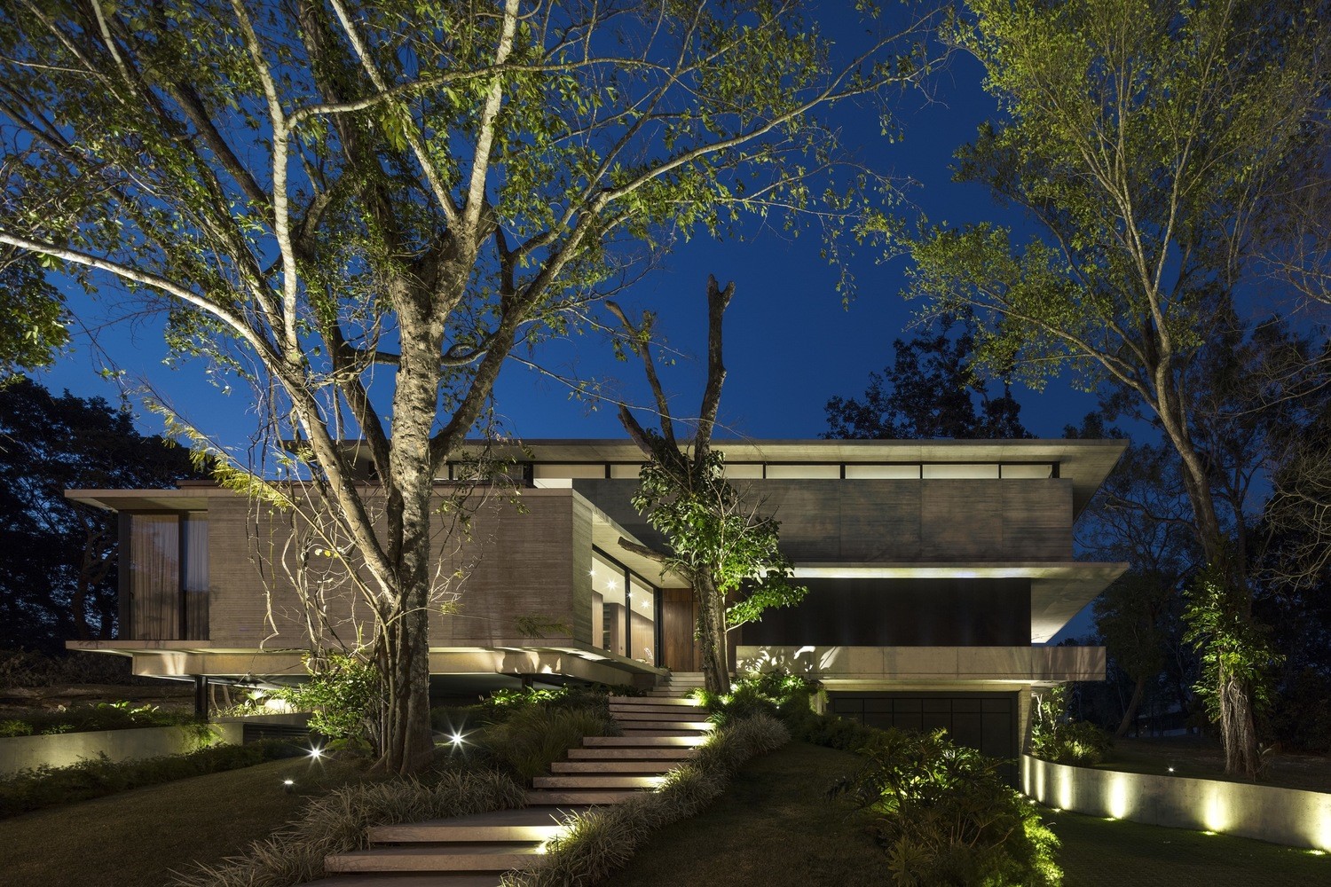 Modern concrete house at night with outdoor lighting HD Wallpaper