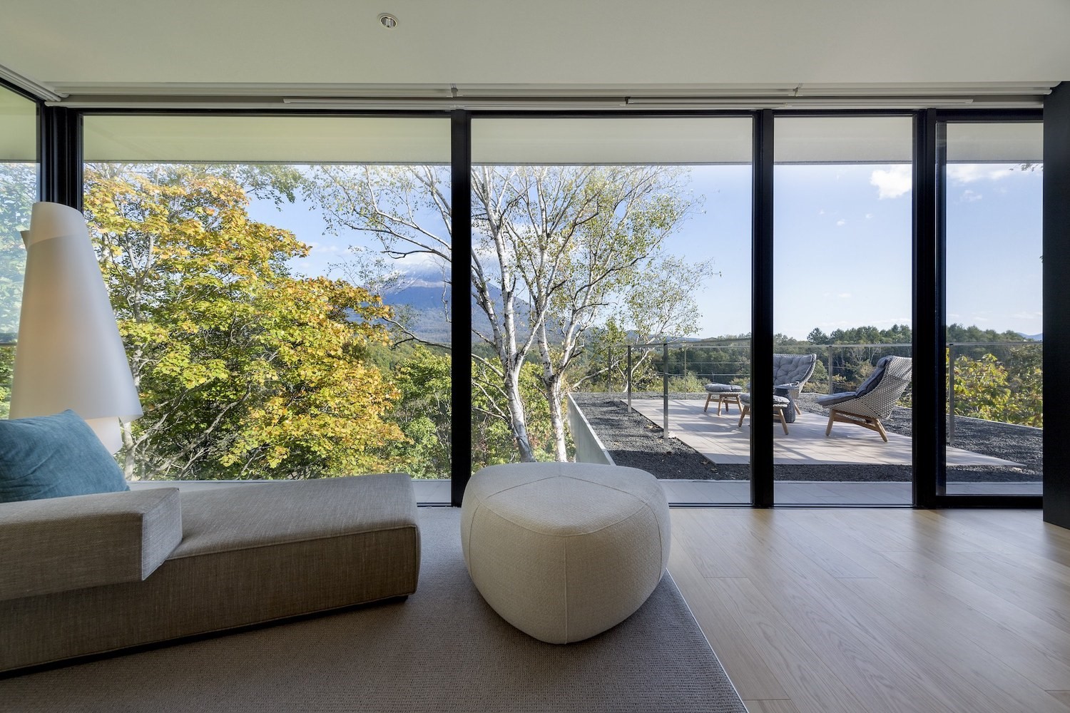 Modern living room with large windows overlooking a forest HD Wallpaper