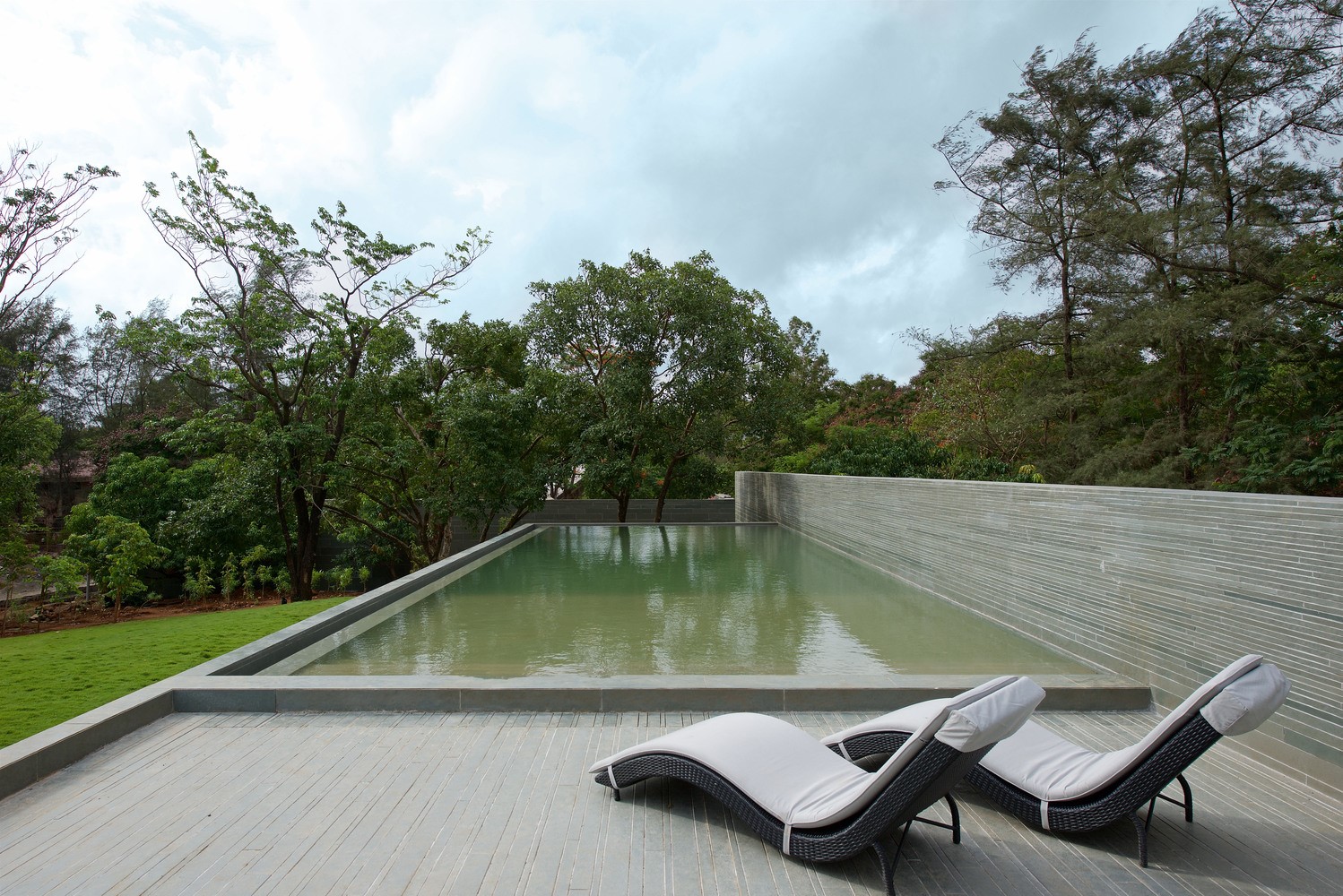 Modern swimming pool with lounge chairs and trees HD Wallpaper