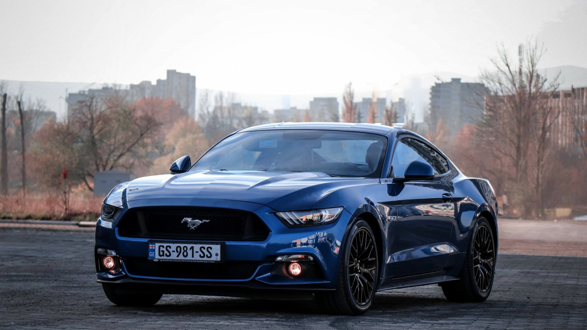 Blue Ford Mustang parked in front of buildings HD Wallpaper