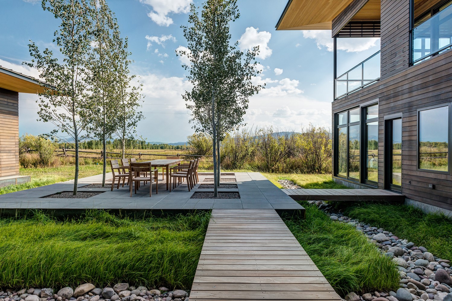 Modern house with outdoor dining area and wooden walkway HD Wallpaper
