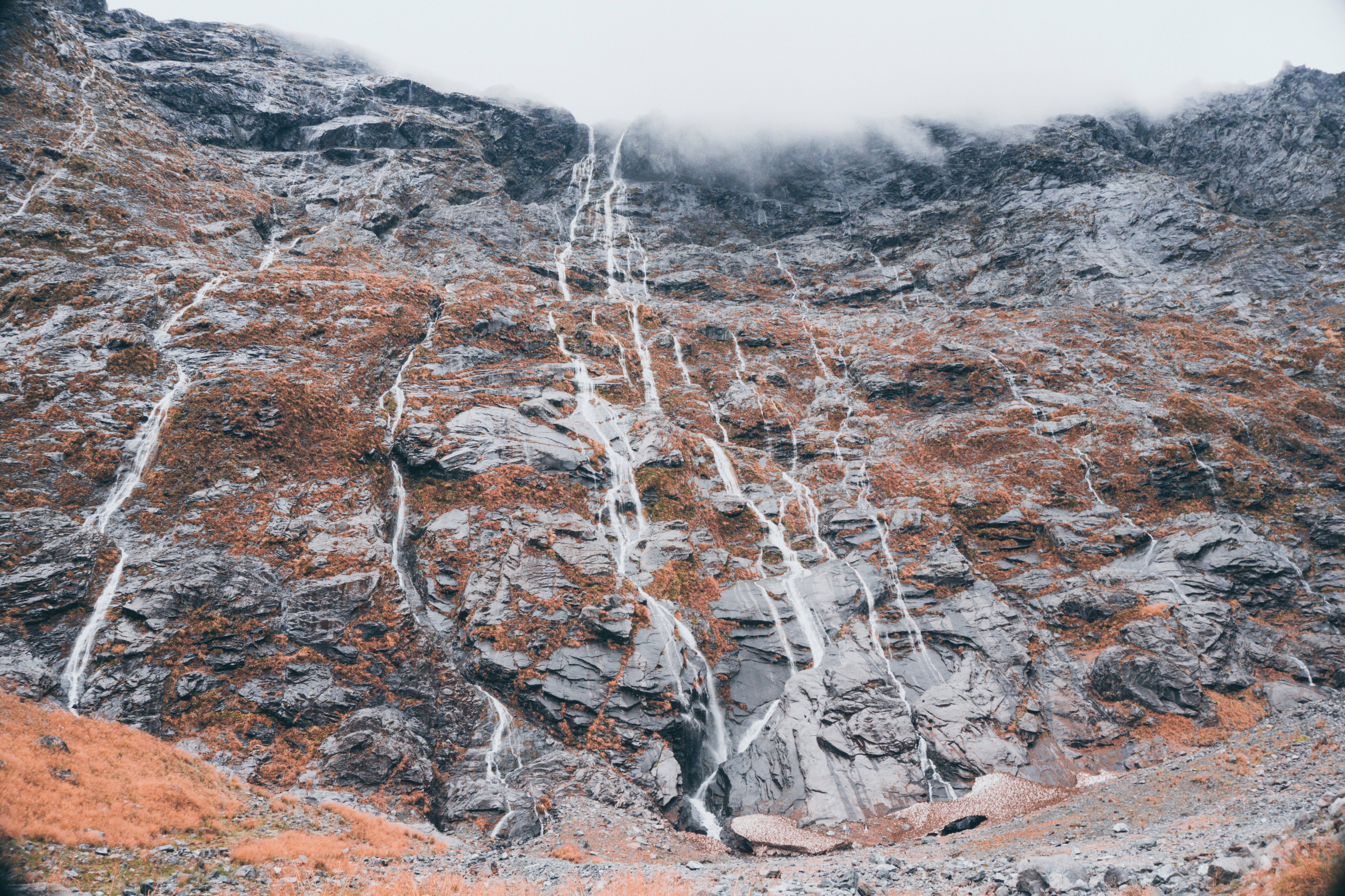 Waterfalls cascading down a rocky mountain in New Zealand HD Wallpaper