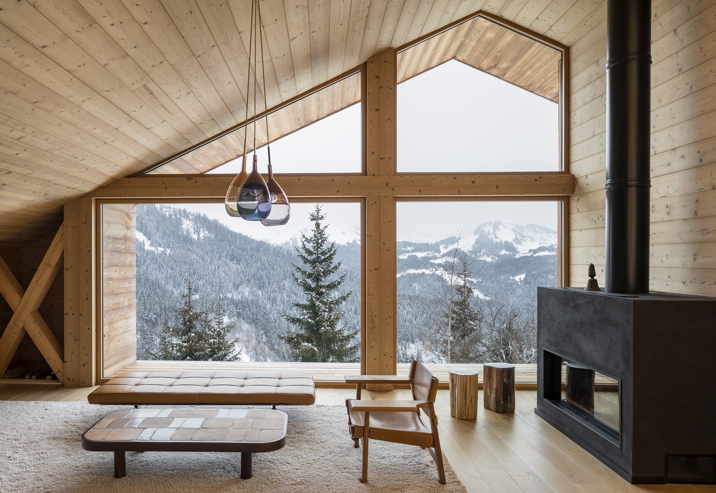 Cozy cabin interior with large windows overlooking snowy mountains HD Wallpaper