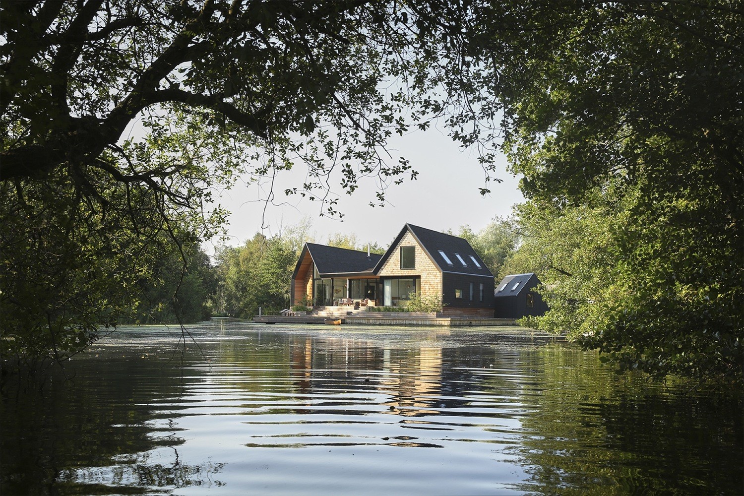 Modern house on a lake surrounded by trees HD Wallpaper