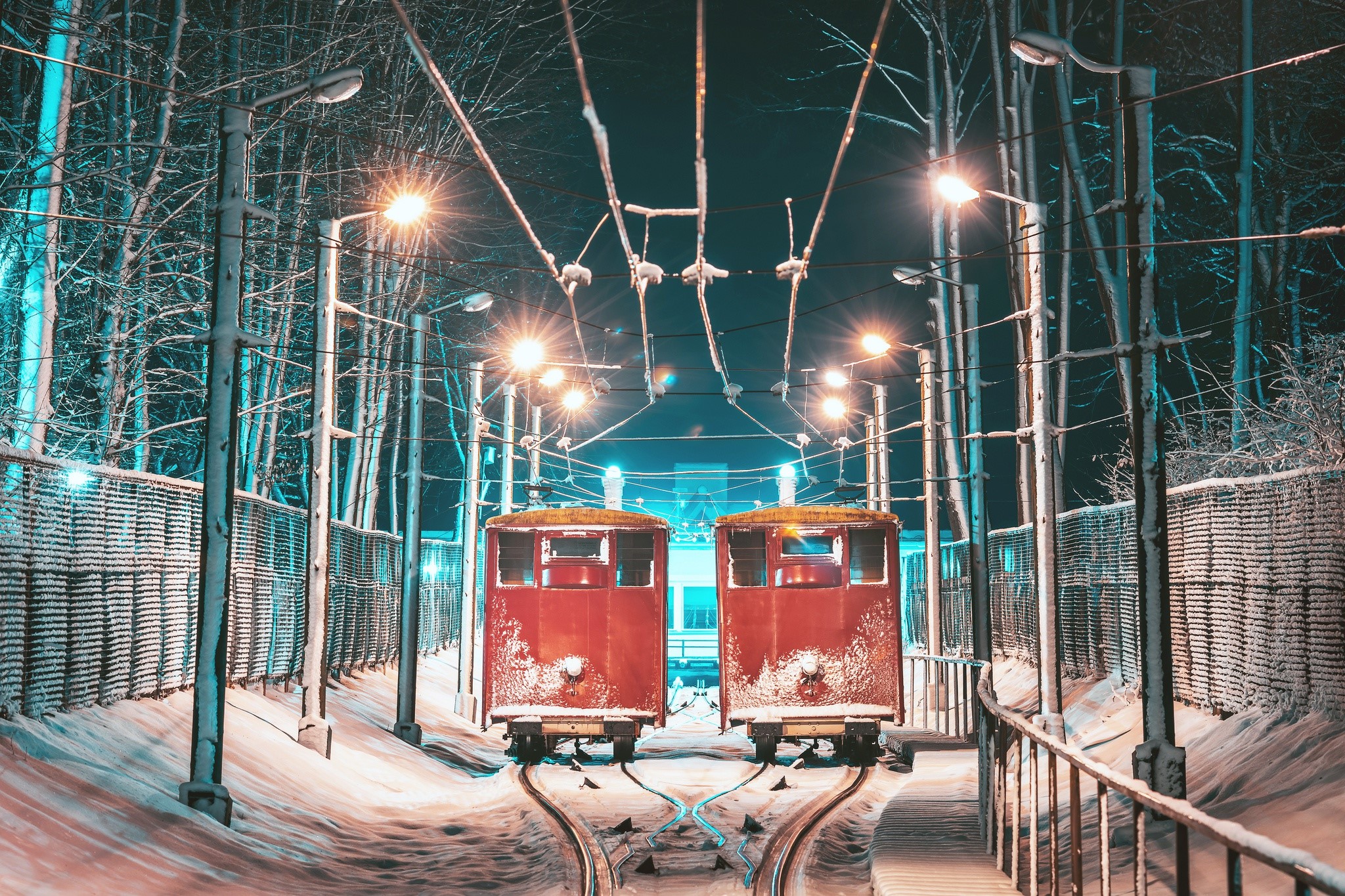 Two red trams on snowy tracks at night in Kaunas HD Wallpaper