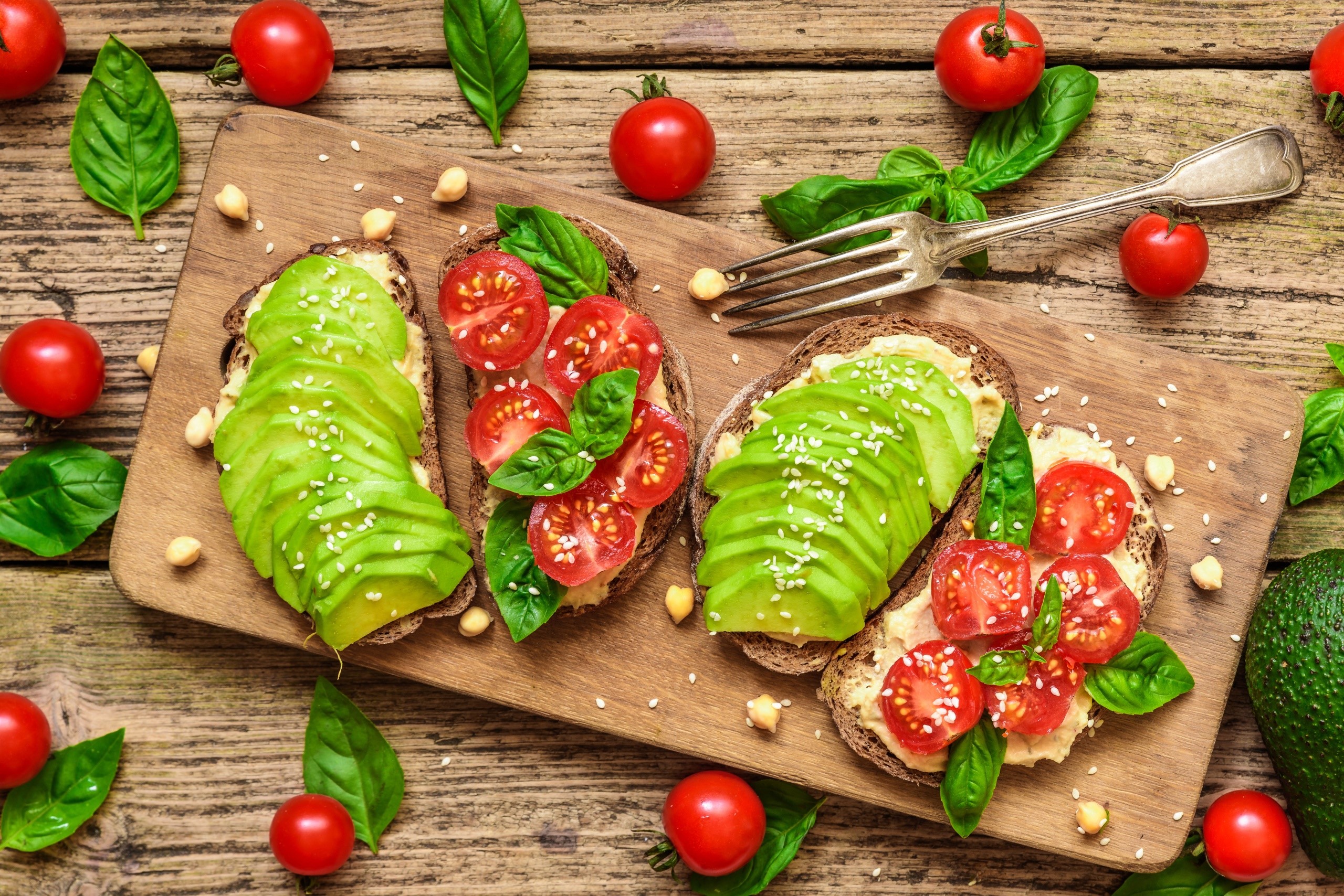 Avocado and tomato toasts on a wooden board with basil HD Wallpaper